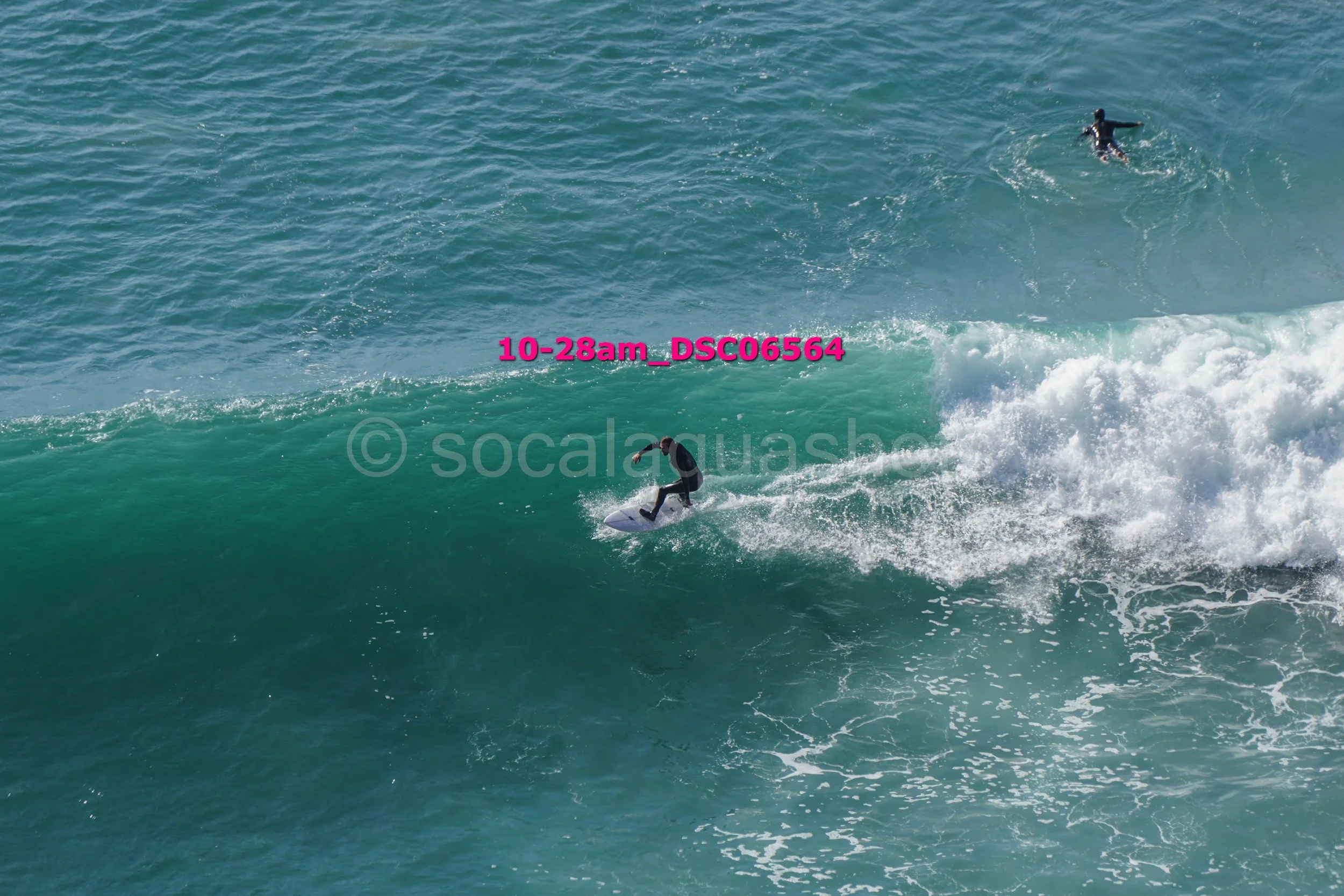 A surfer riding a wave with another surfer in the distance in the water