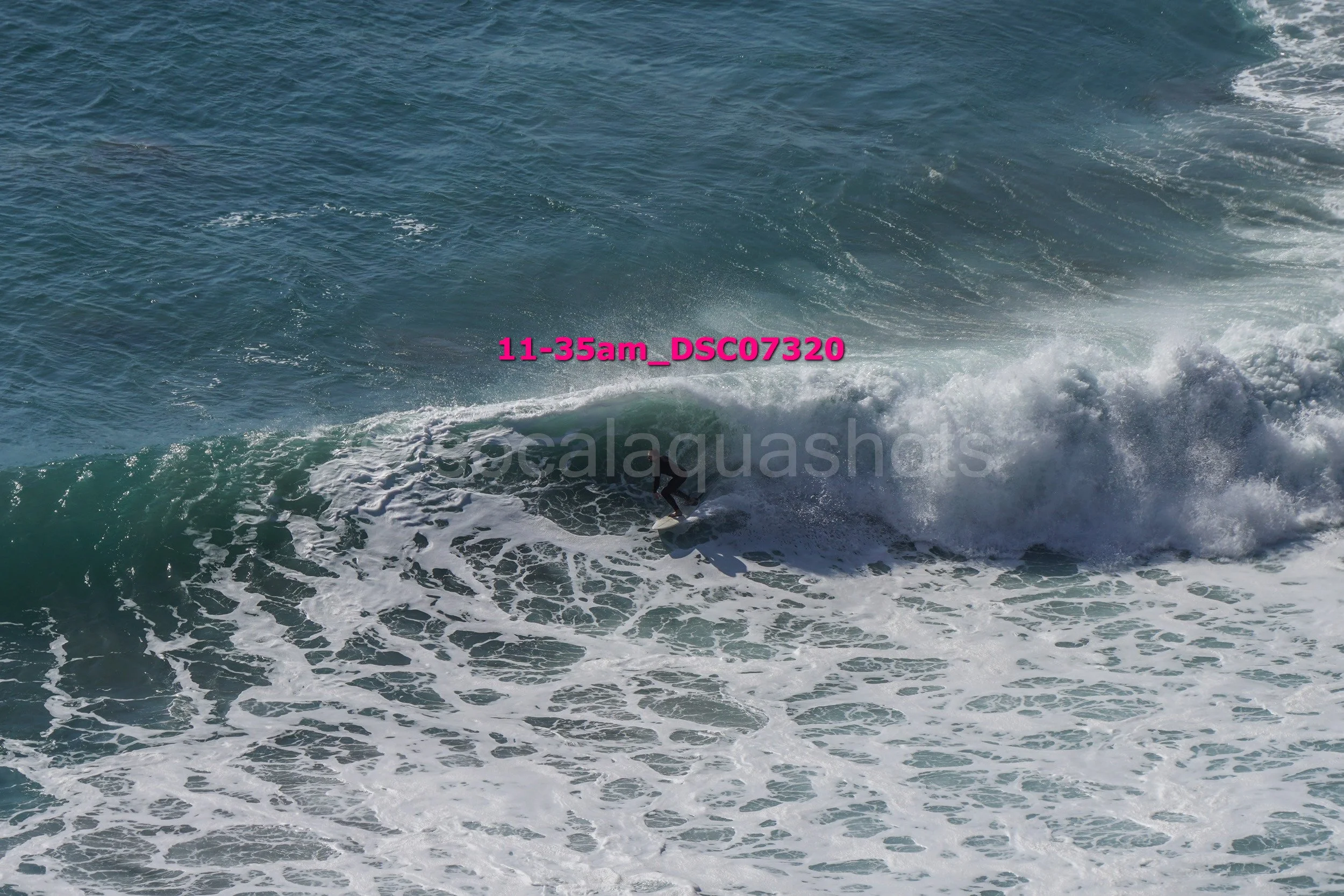 A surfer riding a wave in the ocean with white foam and waves in the background.
