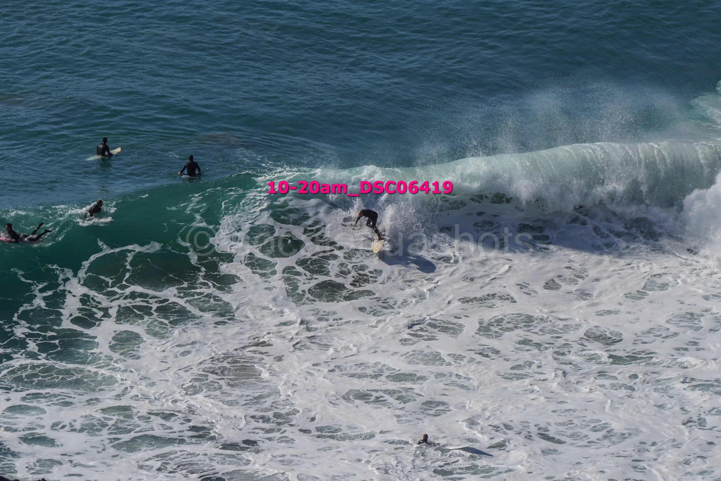 Surfer riding a wave while several surfers are in the water nearby.