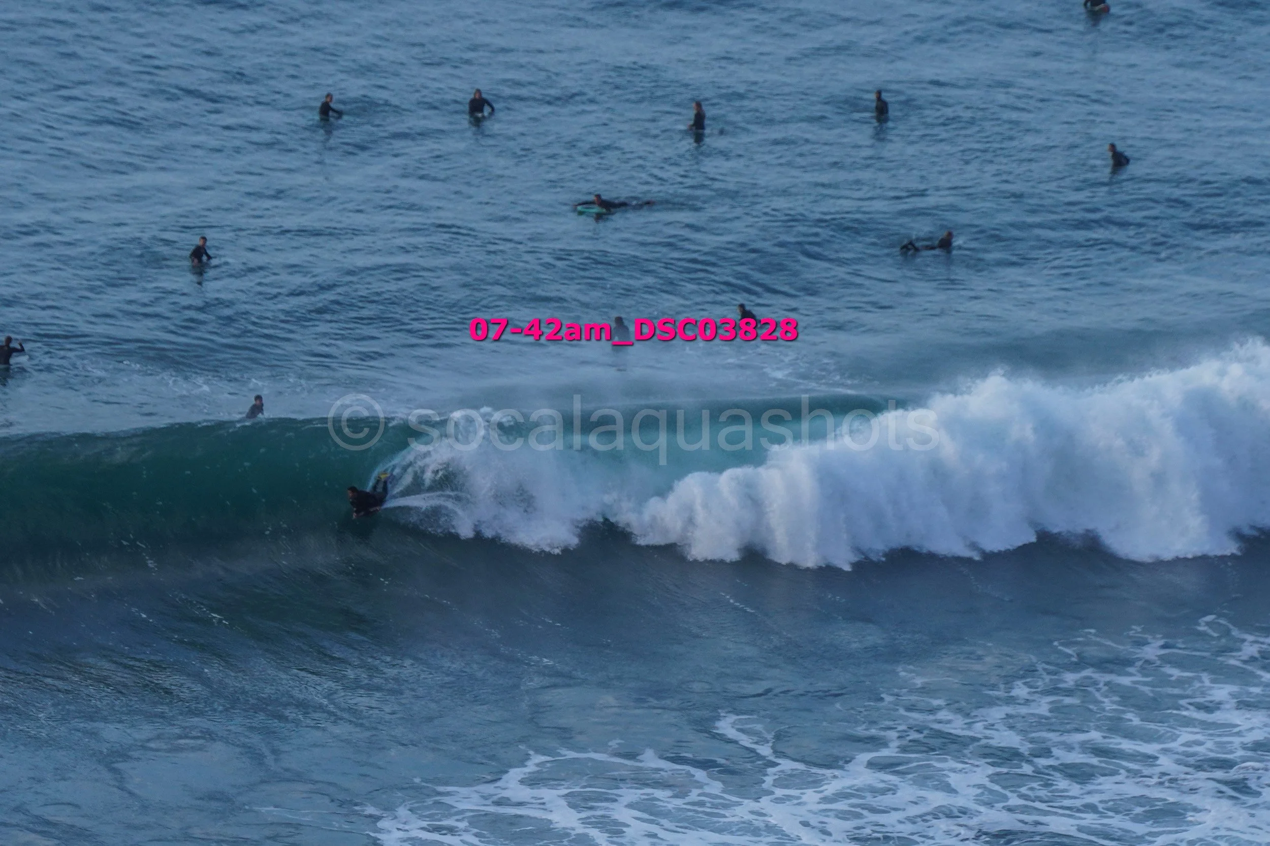 Surfer riding a wave while multiple surfers are in the water in the background.
