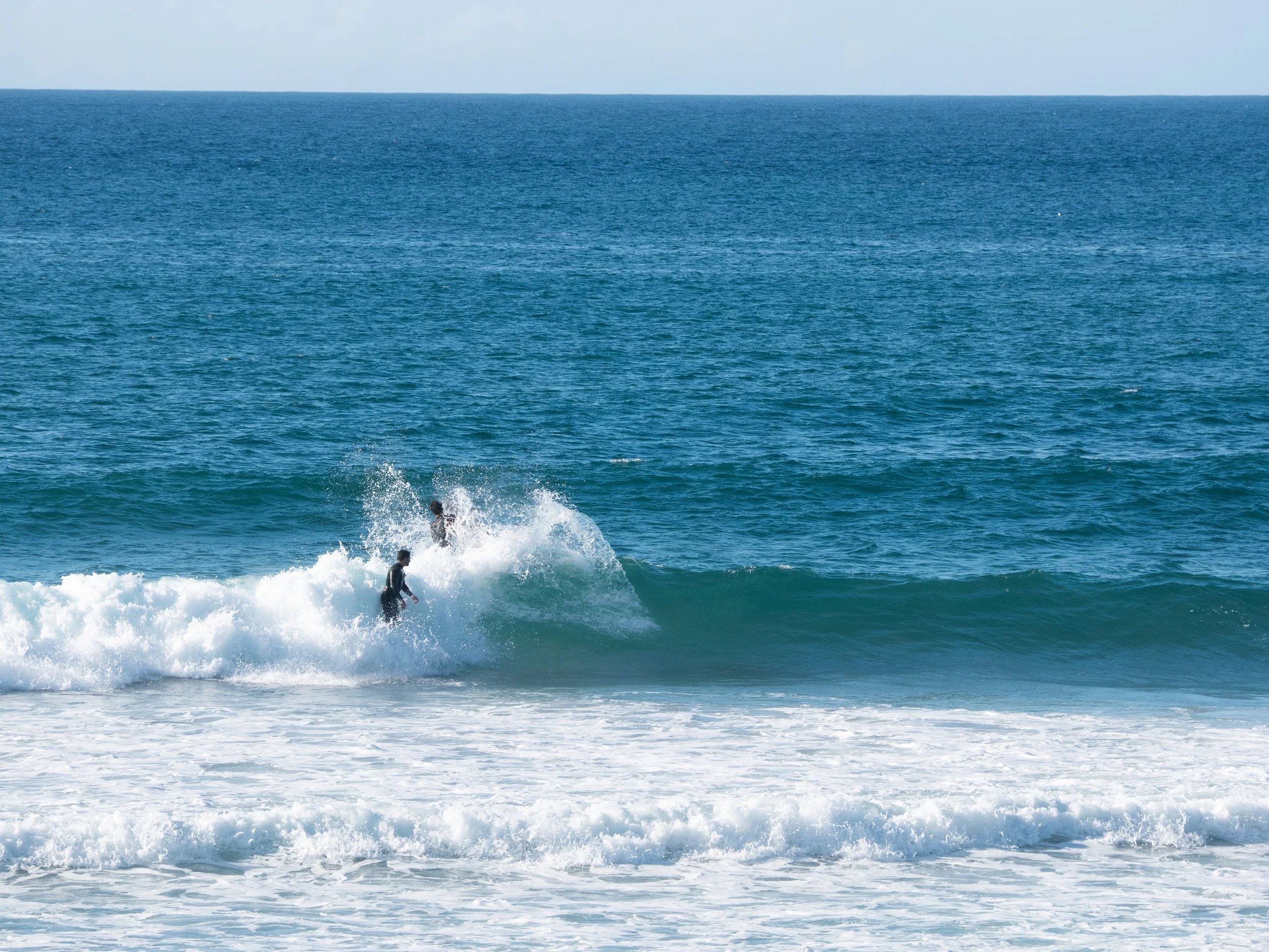 Three surfers riding a wave in the ocean.