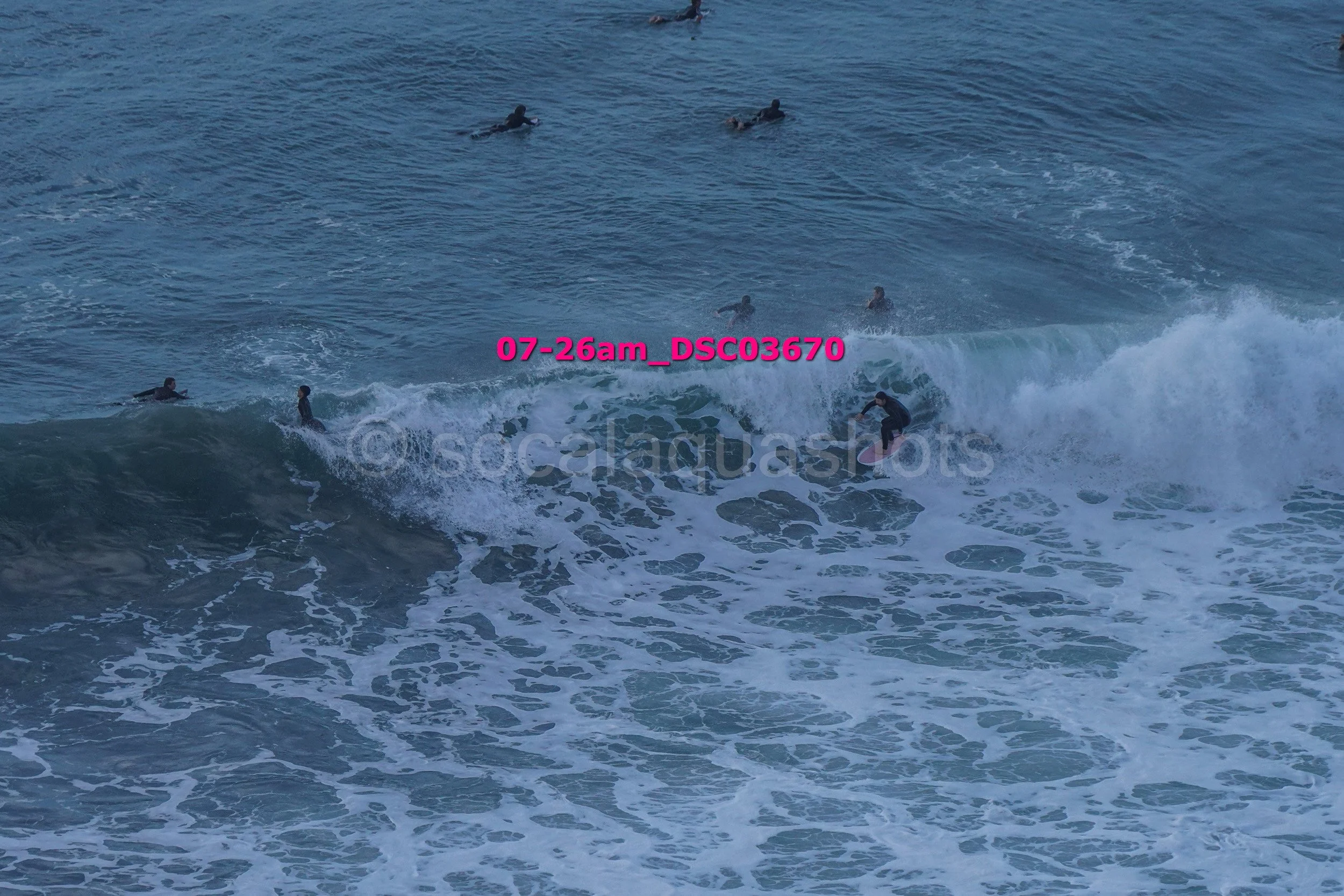 People surfing and swimming in the ocean with waves.