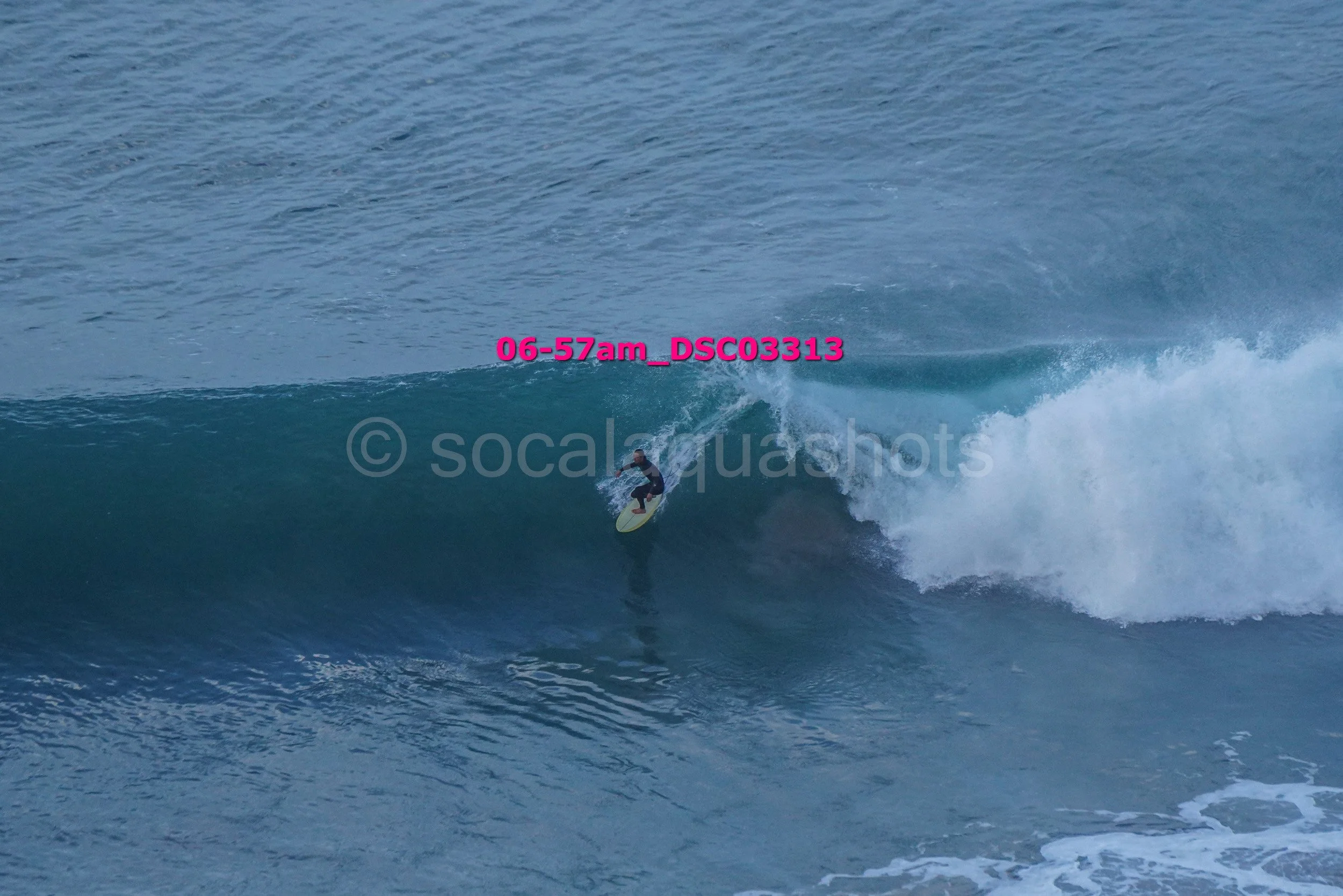 A surfer riding inside the barrel of a large blue wave in the ocean.