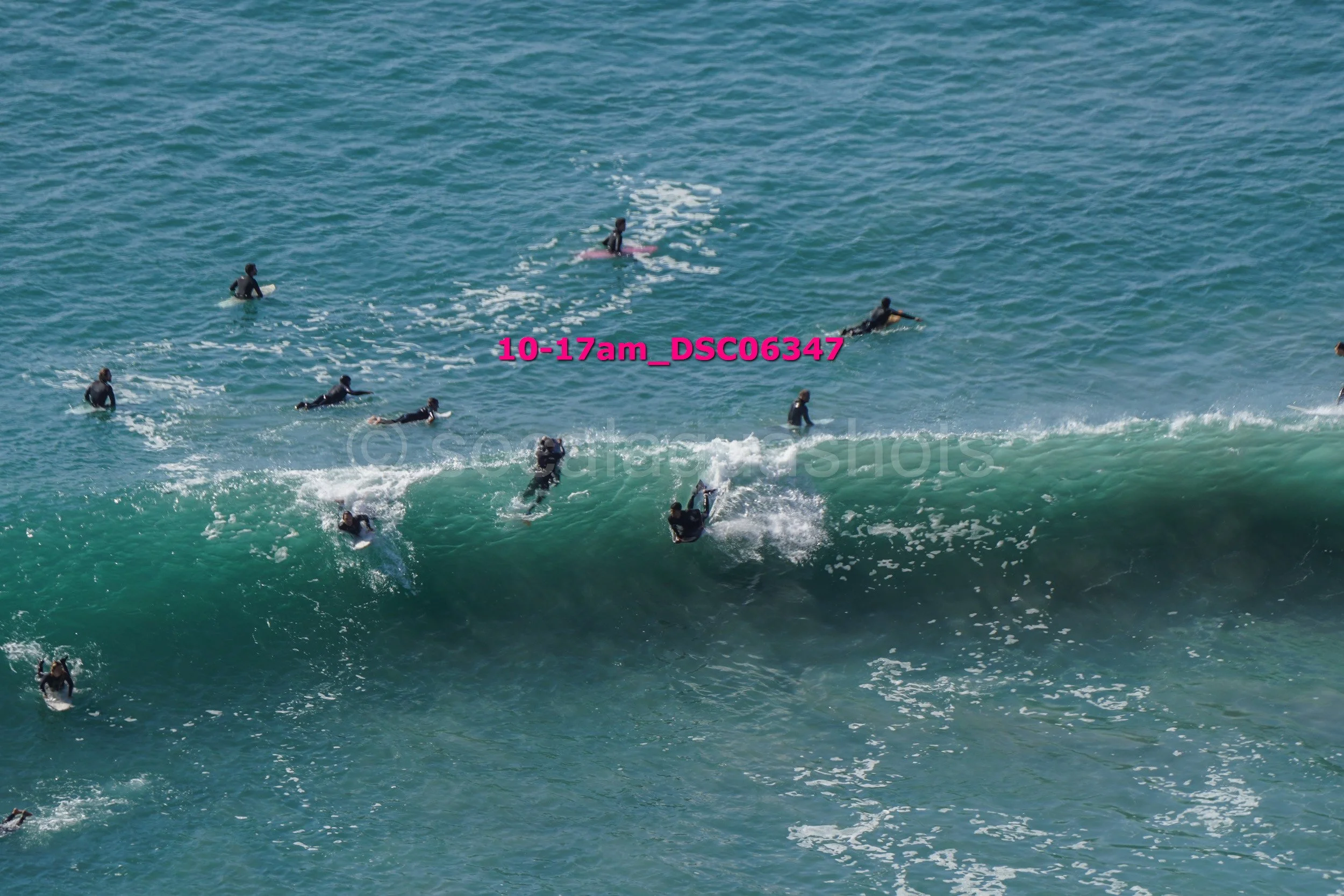 Group of surfers in the ocean catching waves, some paddling and some riding the waves.