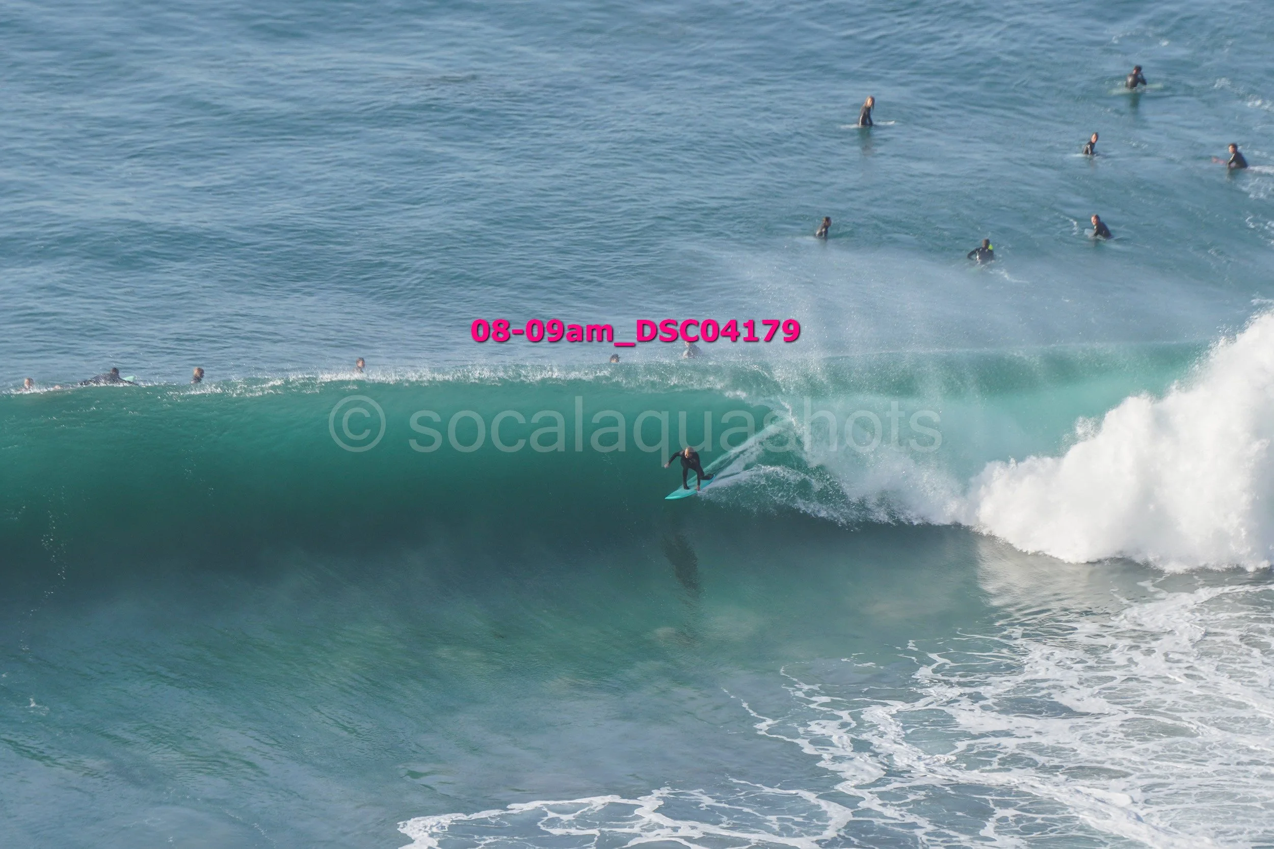 A surfer riding a large wave with multiple surfers in the background in the ocean.