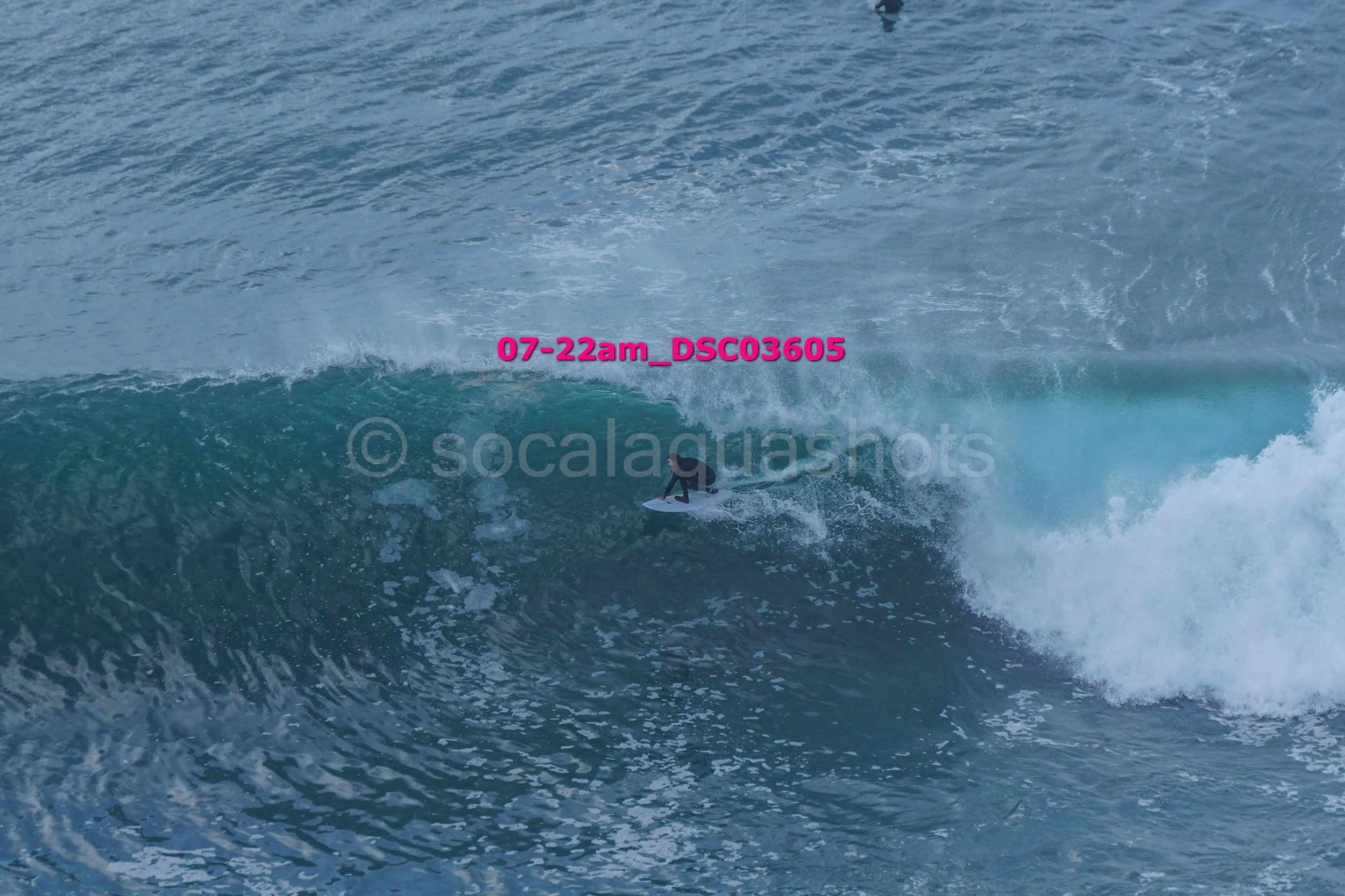 A person surfing on a large ocean wave during daytime.