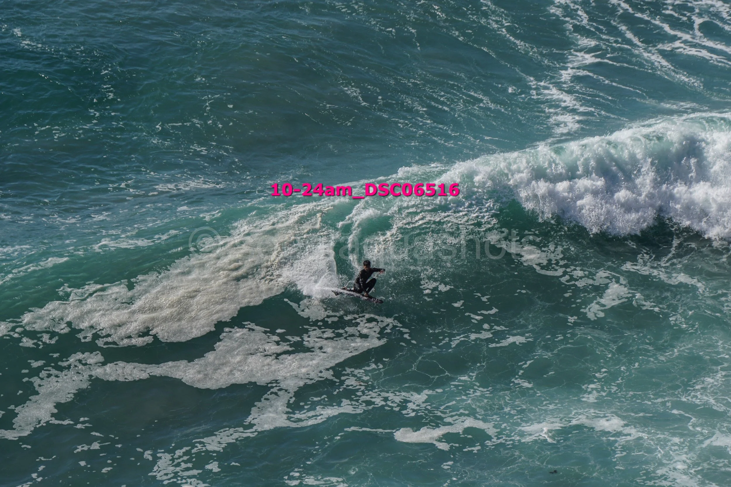 Surfer riding a wave in the ocean with white foam and blue water.