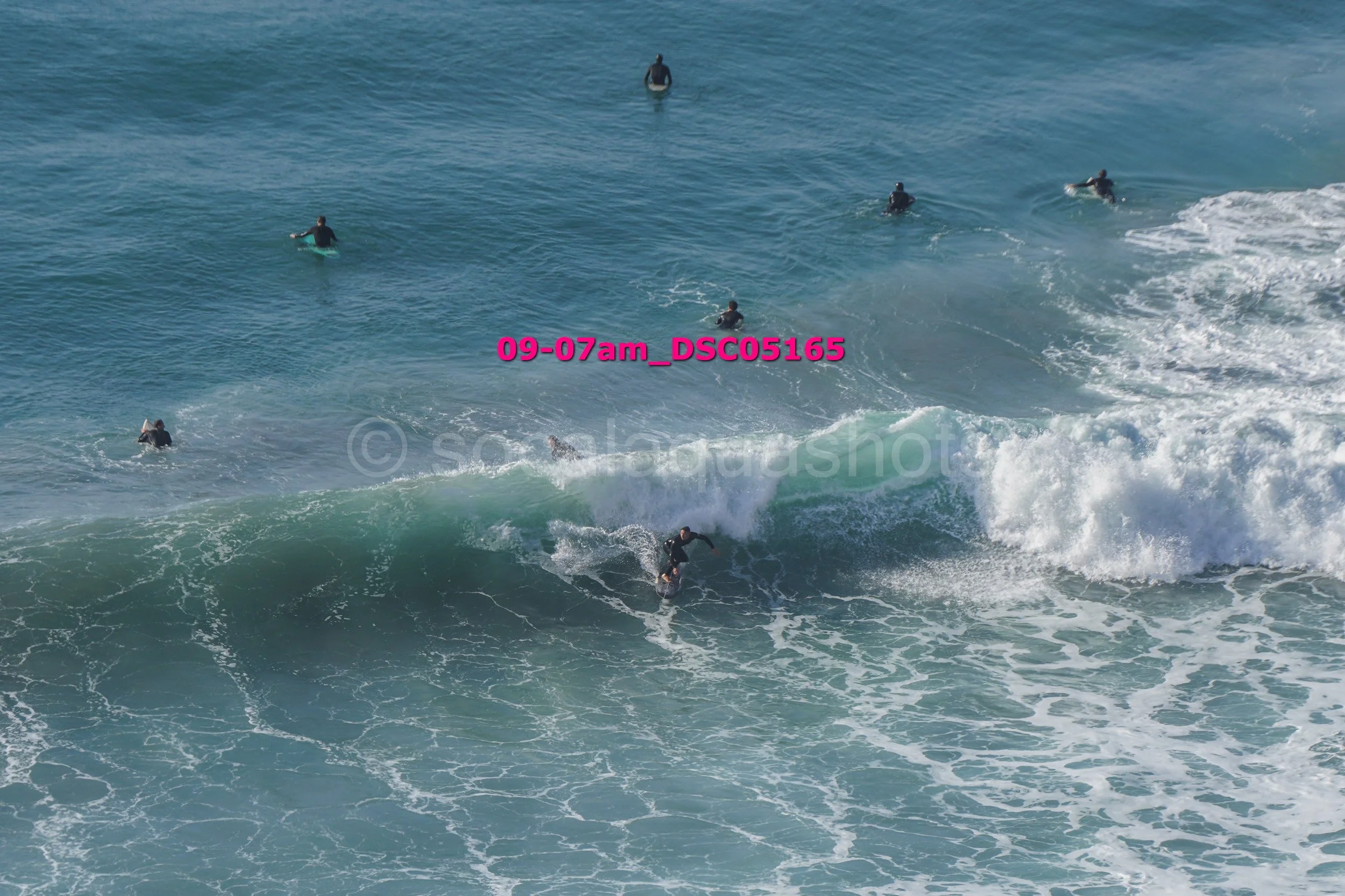 Surfers riding and paddling in the ocean waves.