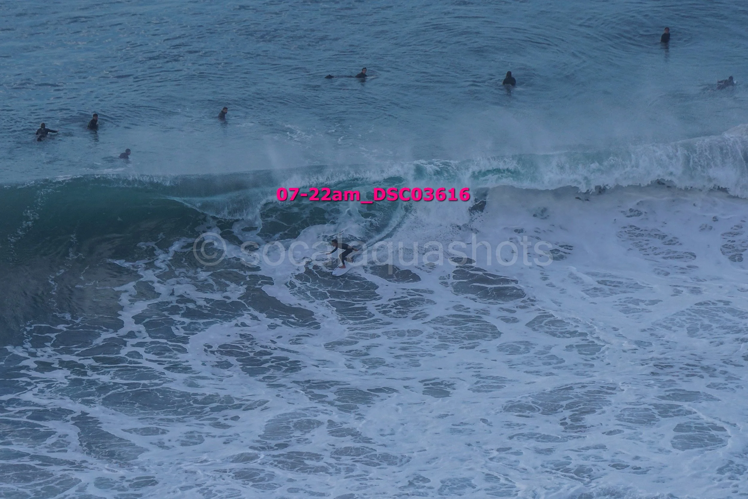 Surfers riding and waiting for waves at the ocean.