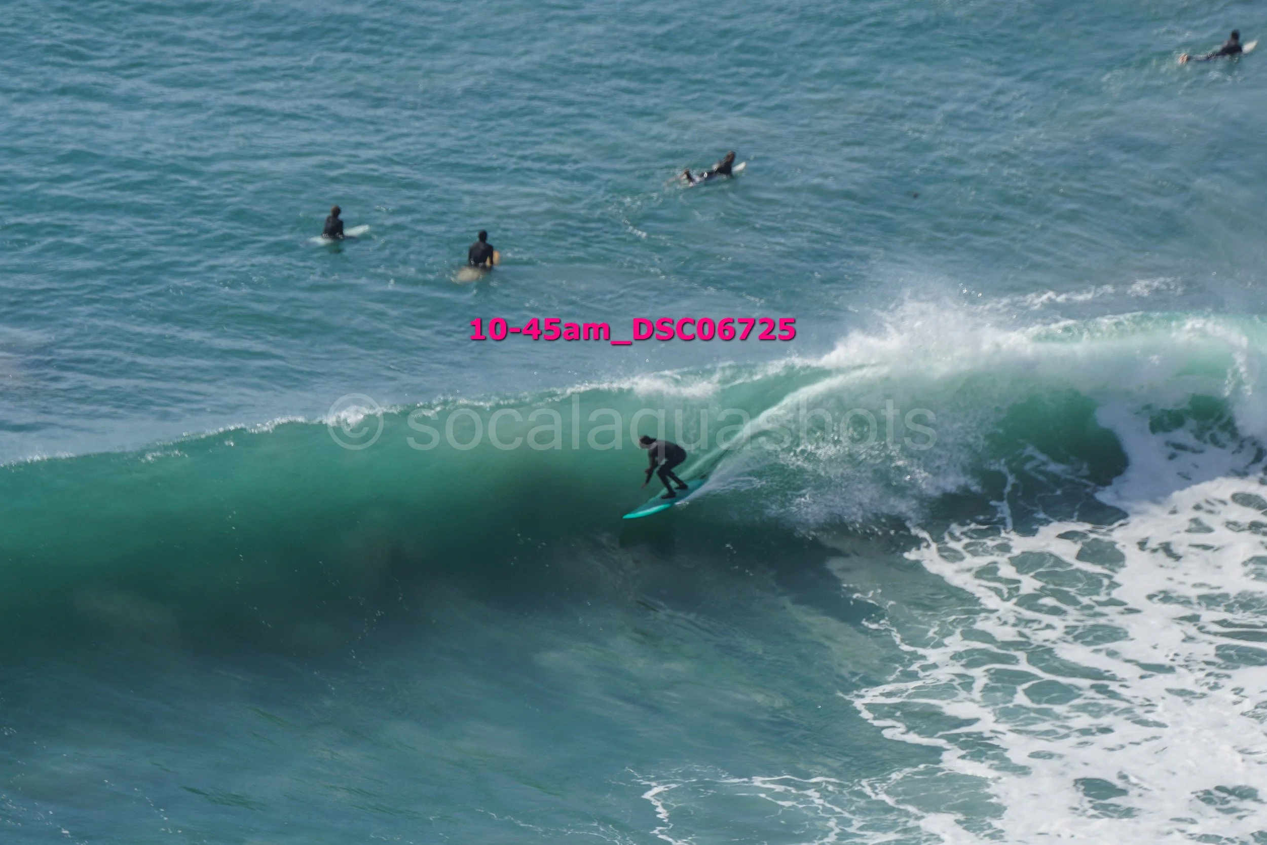 Surfer riding a wave in the ocean with several people in the background on surfboards