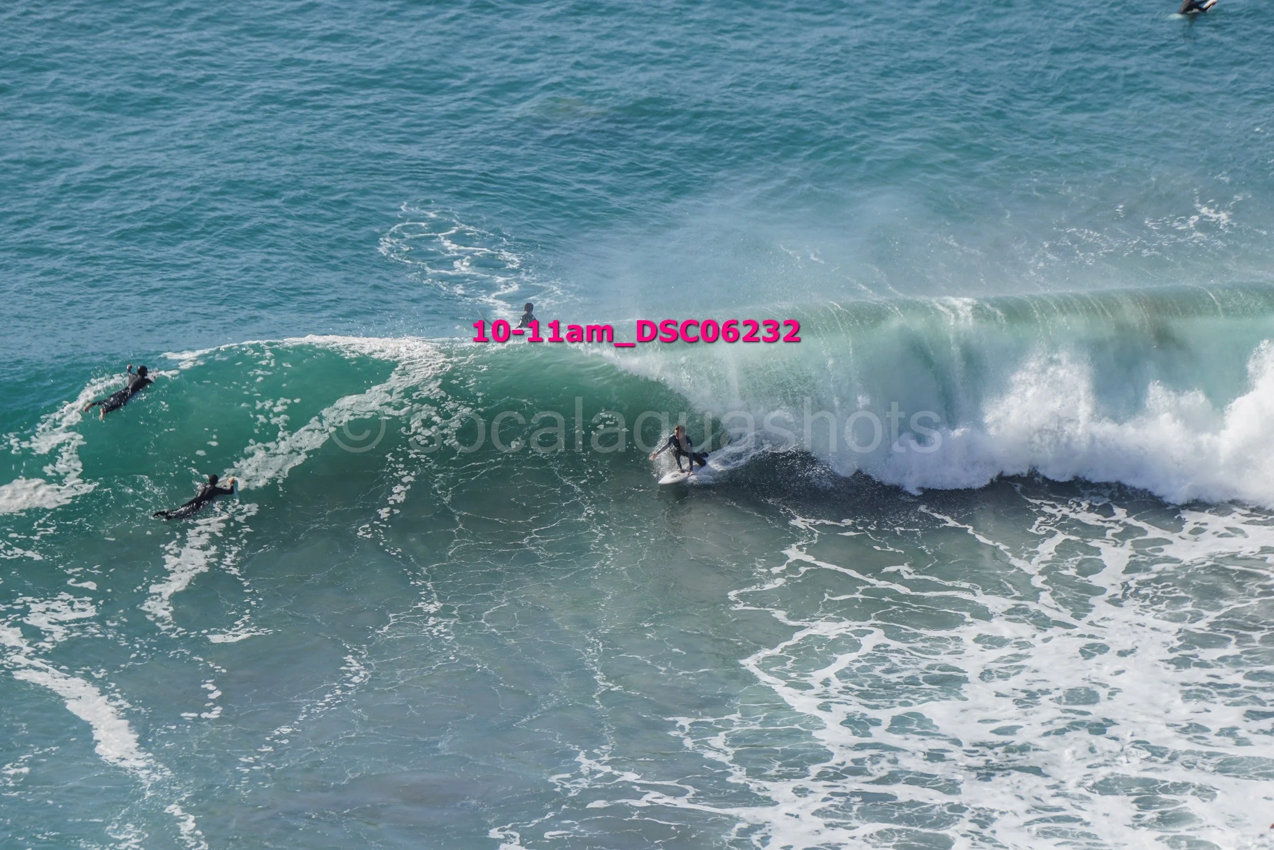 Multiple surfers riding on large ocean waves during daytime.