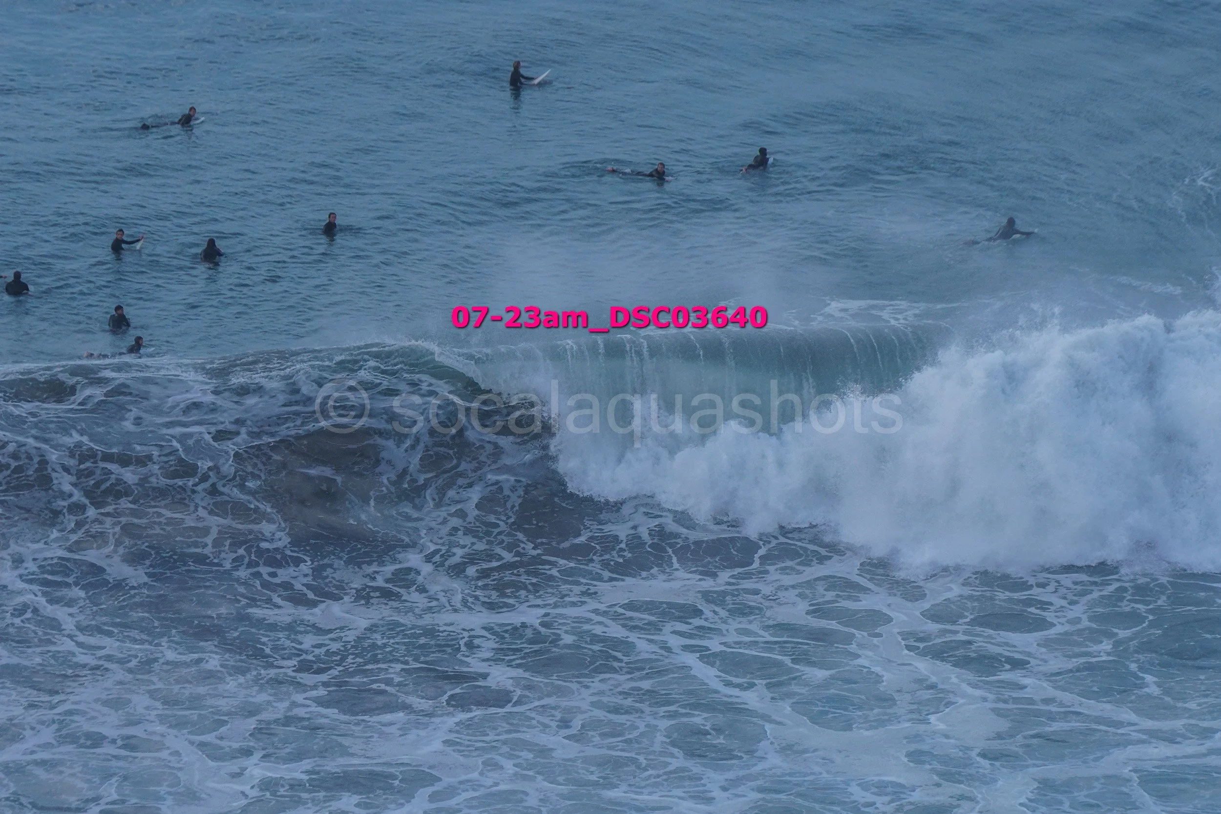 Multiple people swimming and surfing in the ocean with waves near the shore.