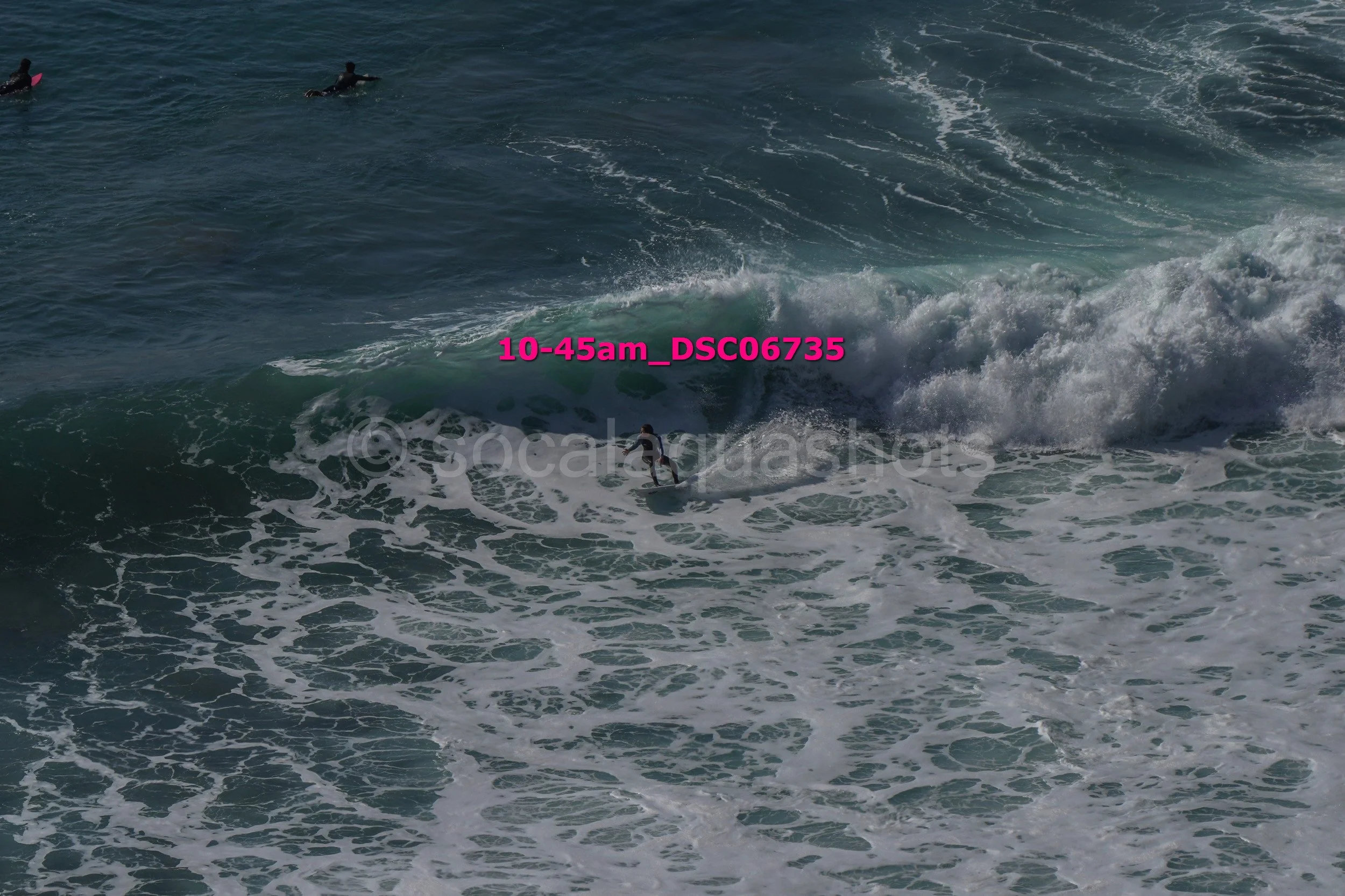 A person surfing on a wave with others in the distance in the ocean.