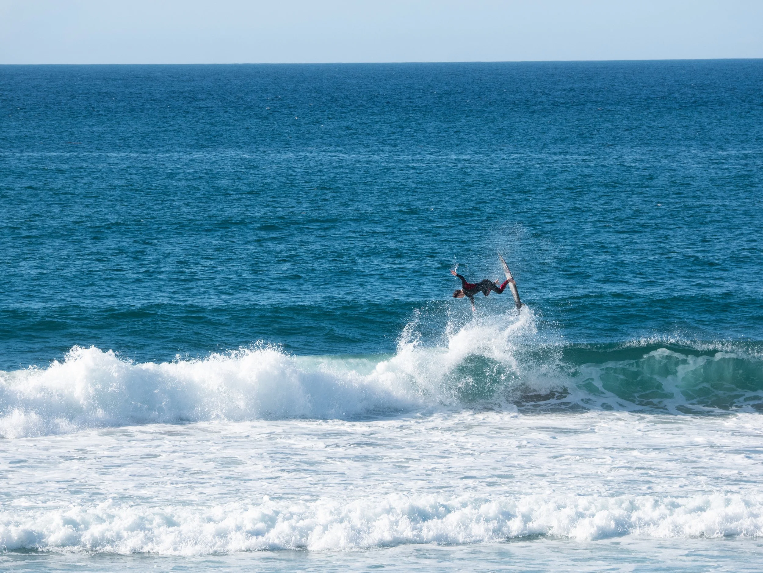 Person performing a flip on a surfboard in the ocean waves.