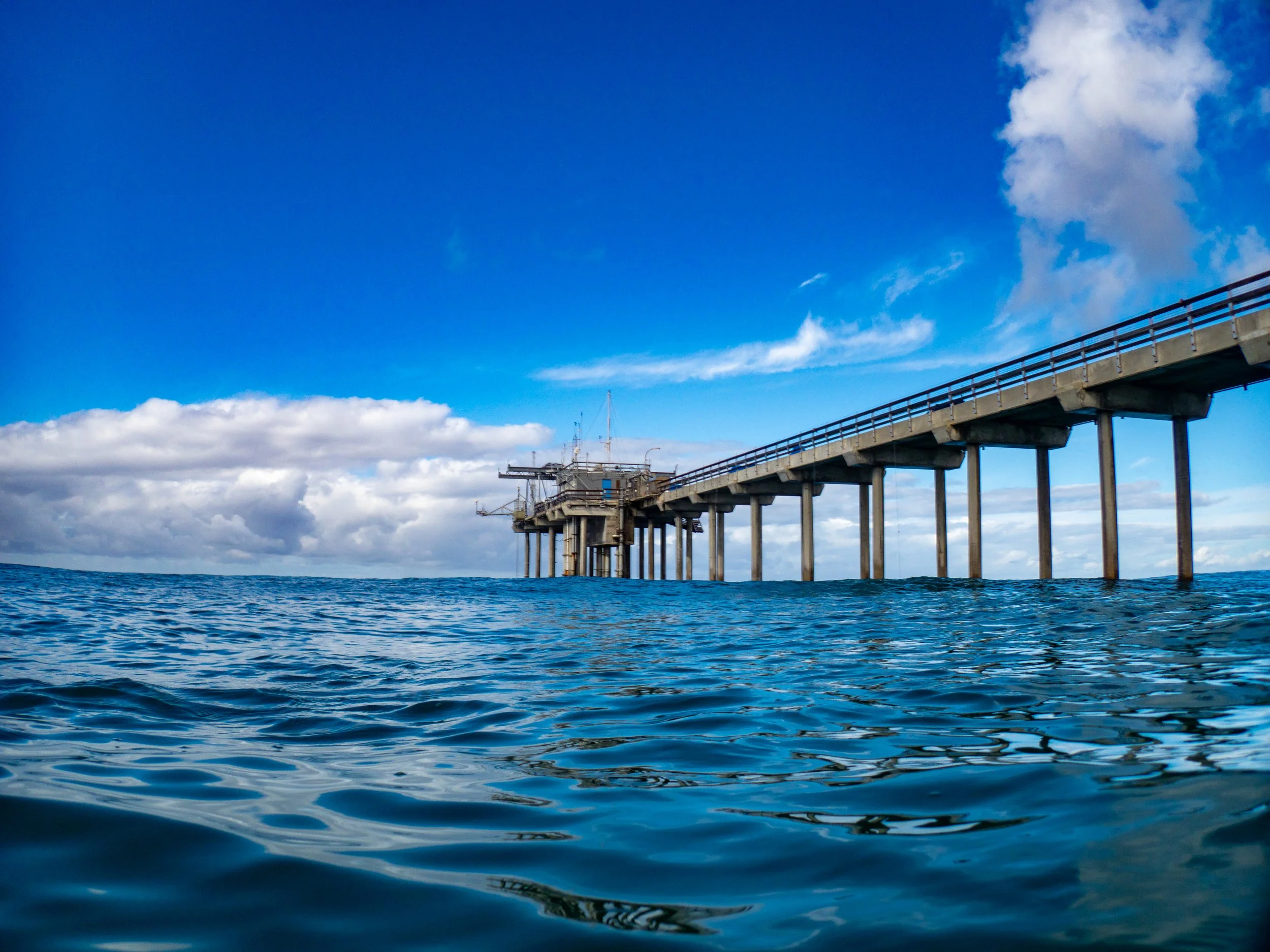 An offshore oil rig in the ocean under a partly cloudy sky.