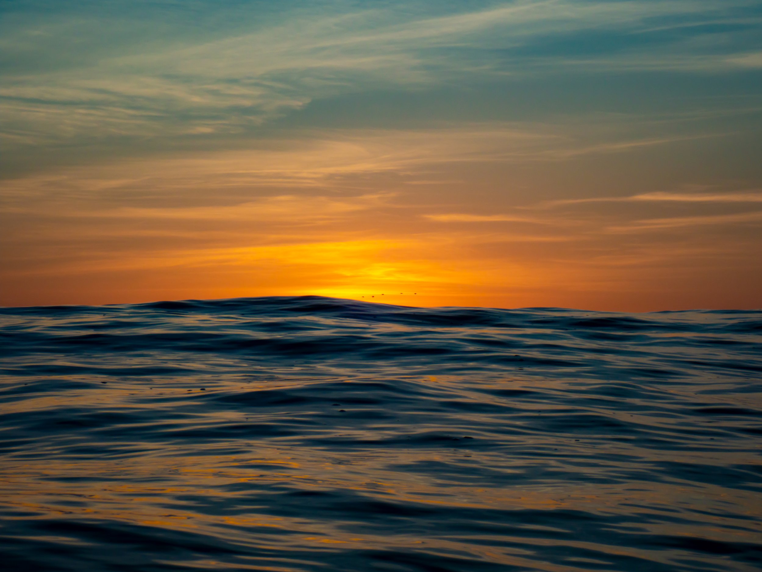 Ocean waves at sunset with an orange and blue sky