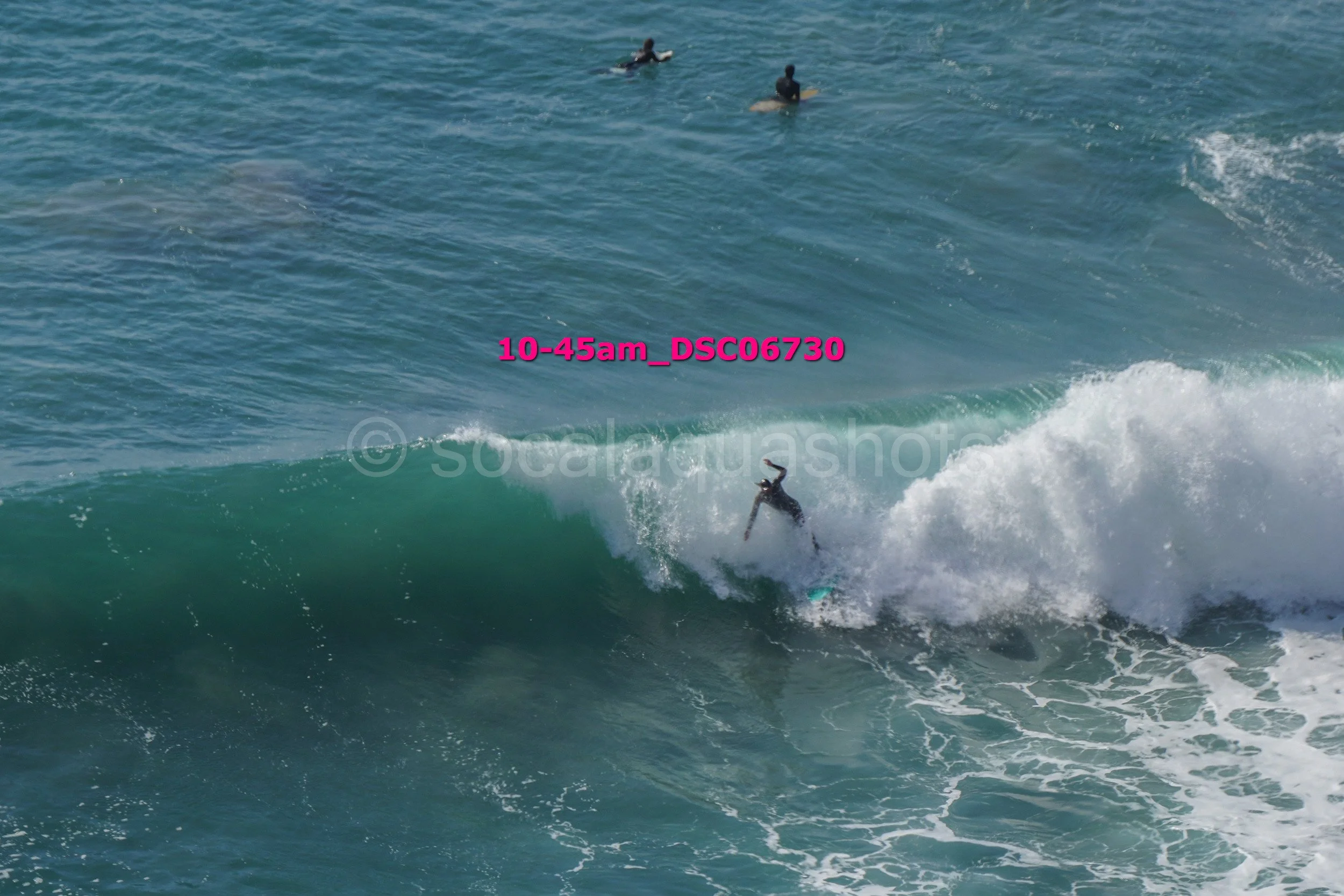Surfer riding a wave with four people swimming in the water in the background.