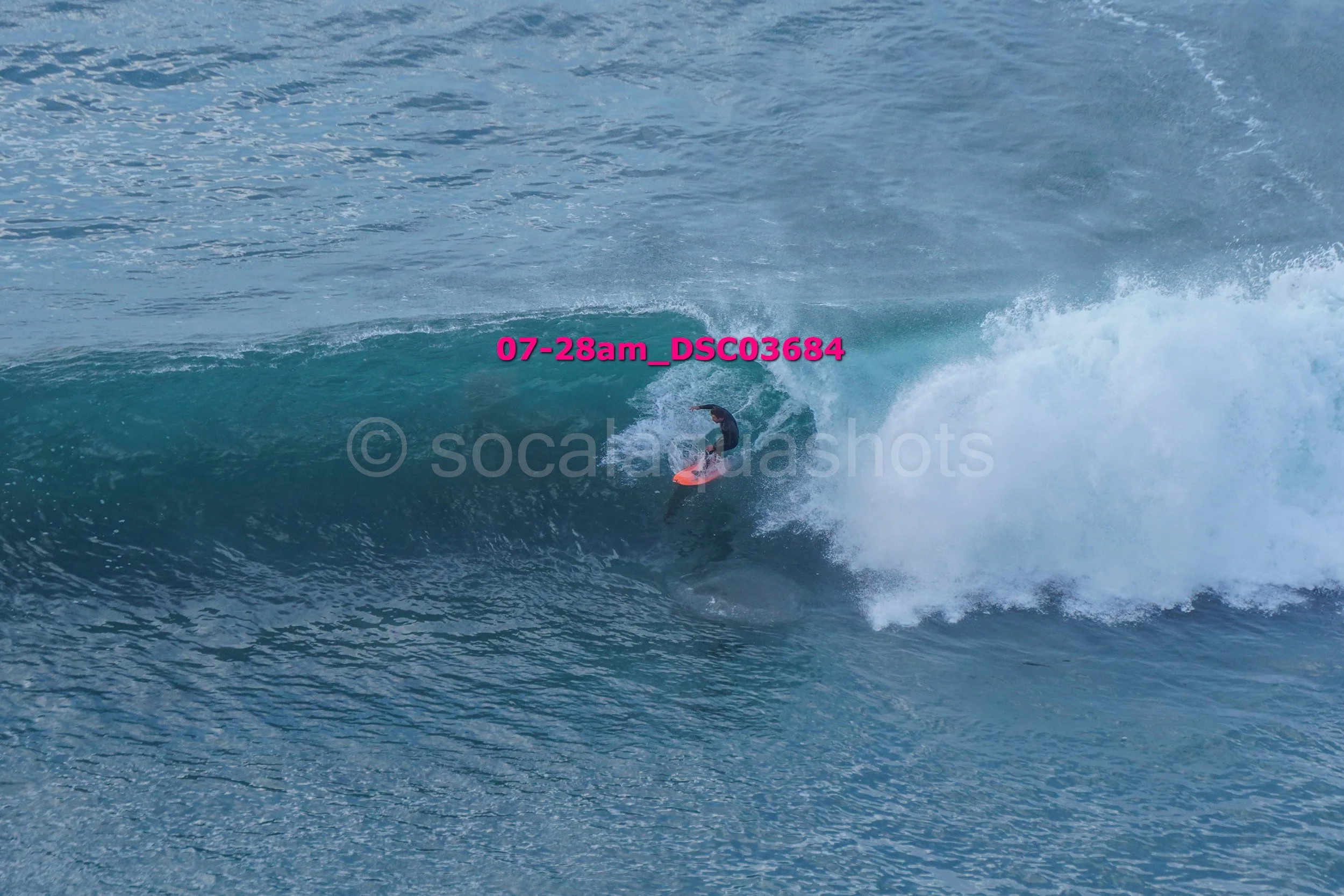 A person surfing on a large blue wave in the ocean.