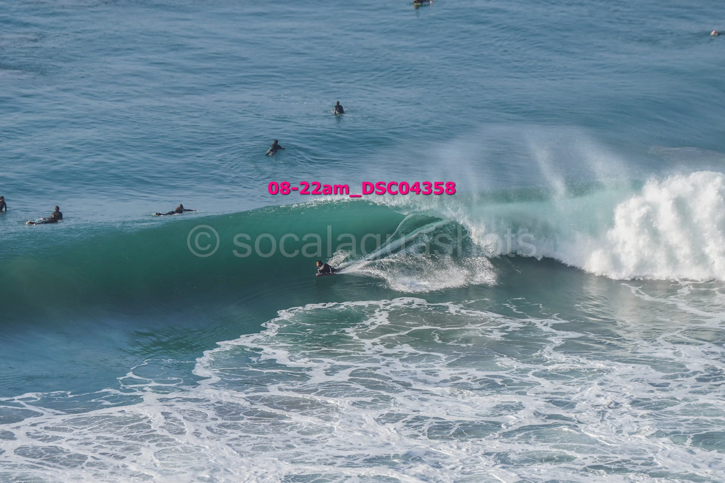 Surfer riding a wave with several surfers in the water in the background.