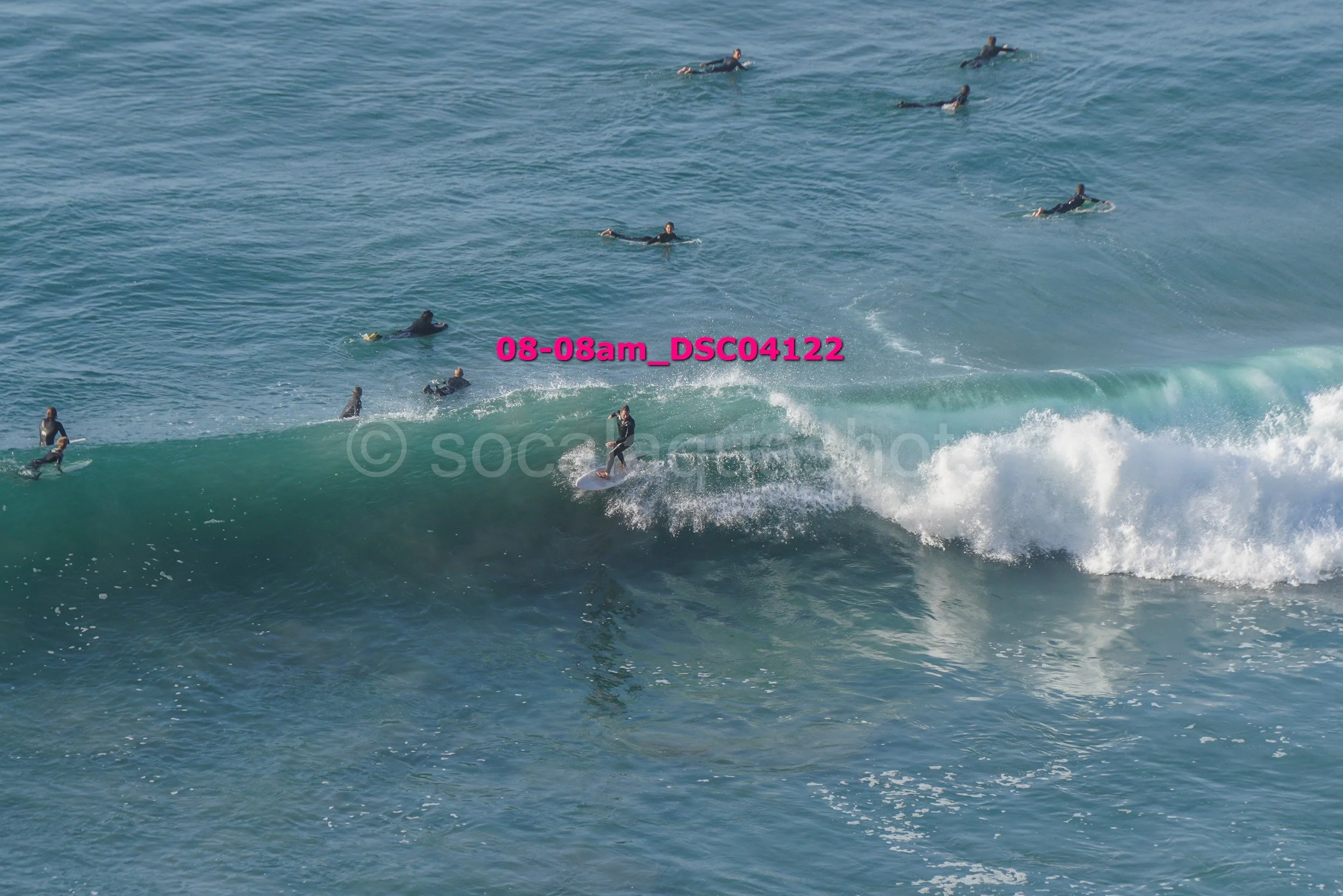 Surfers riding and waiting for waves in the ocean.