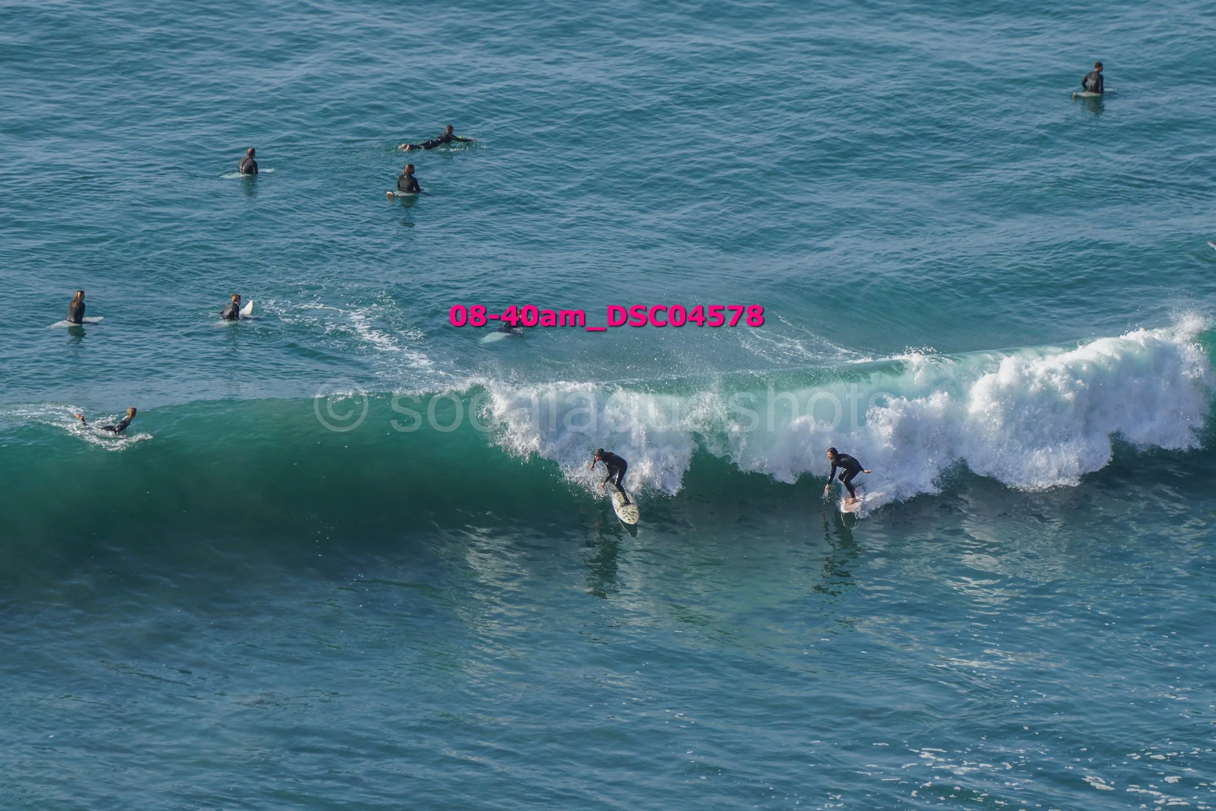 Several surfers riding and waiting for waves in the ocean during daylight.