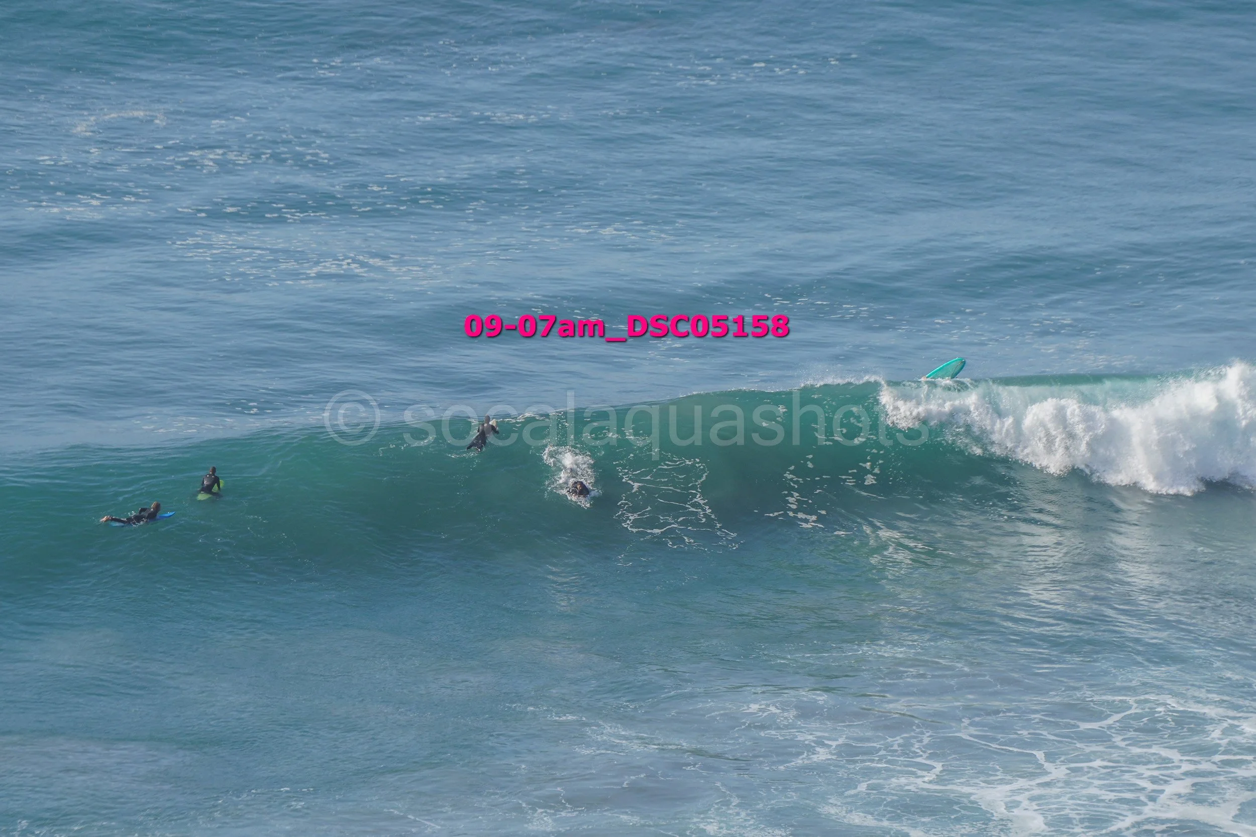 People surfing large ocean waves at the beach in the morning.
