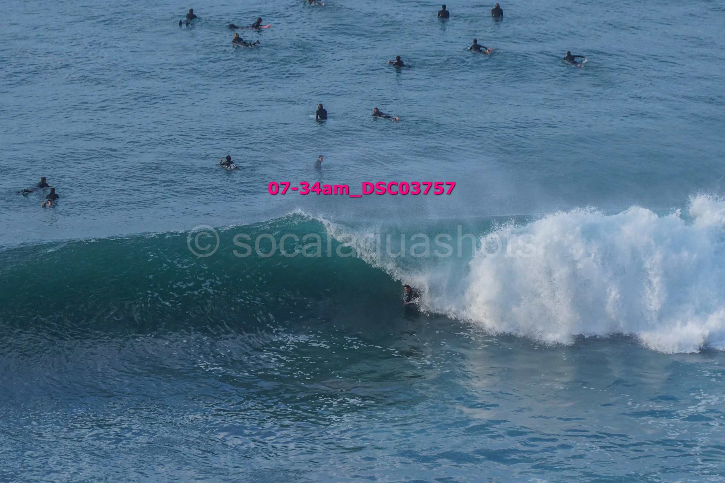 Surfer riding a wave with multiple surfers in the water in the background.