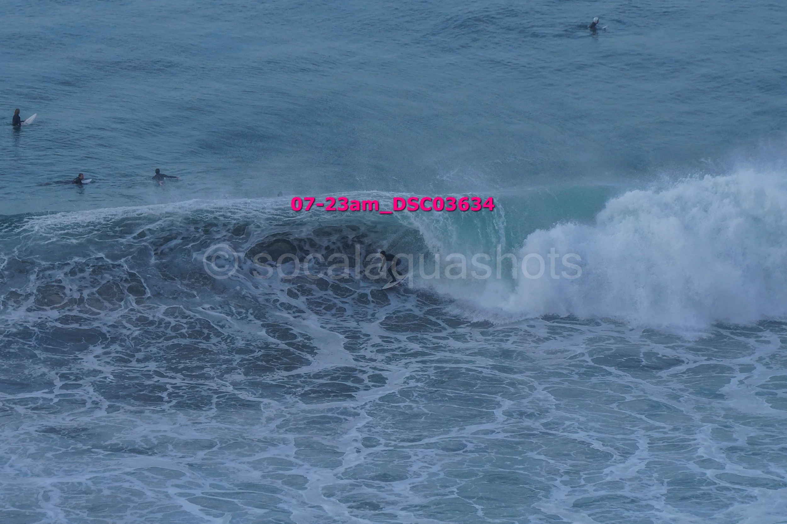 People surfing in the ocean with waves, some surfers waiting and riding waves.