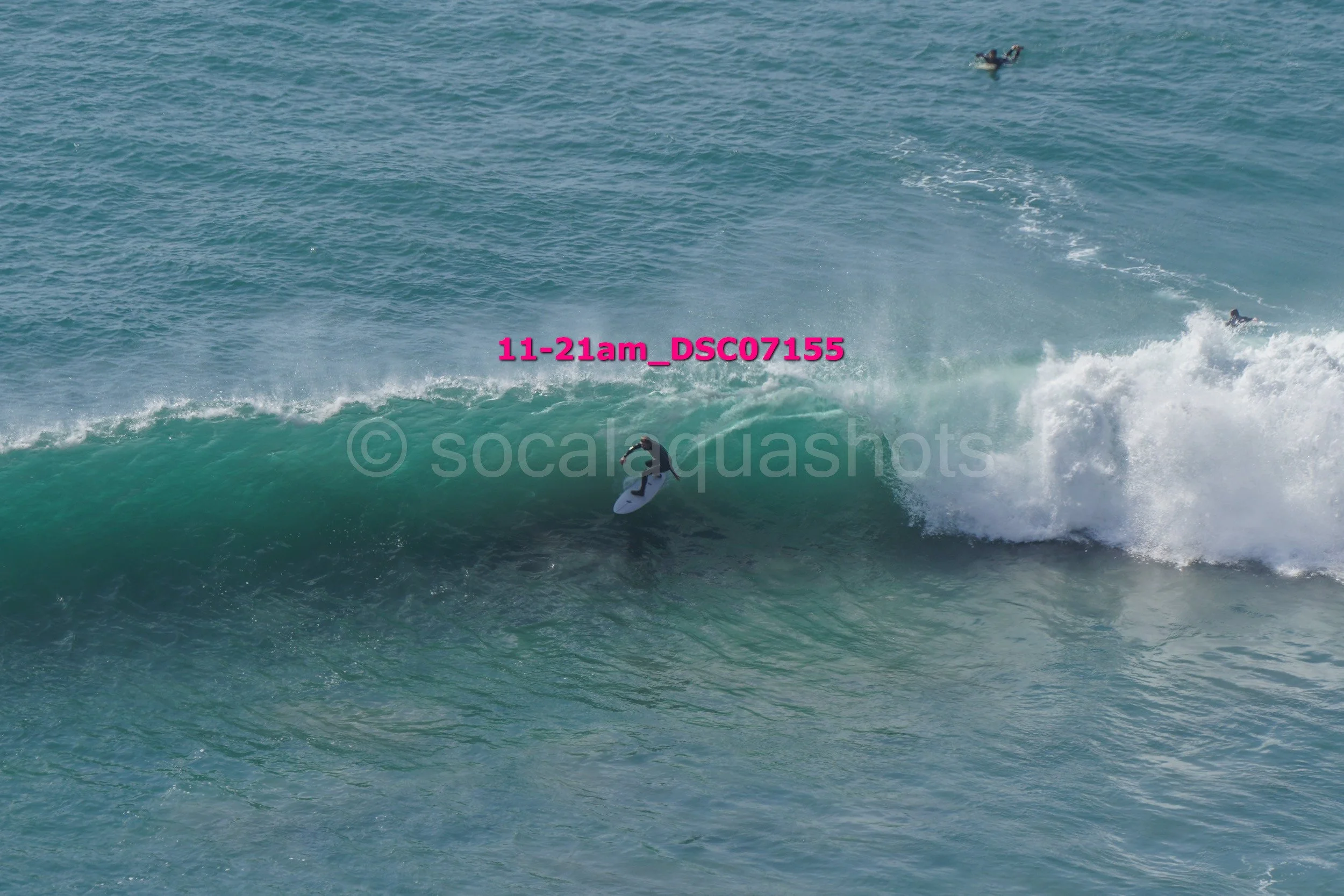 A surfer riding a wave near the shoreline with three other surfers in the water and two more out in the ocean.
