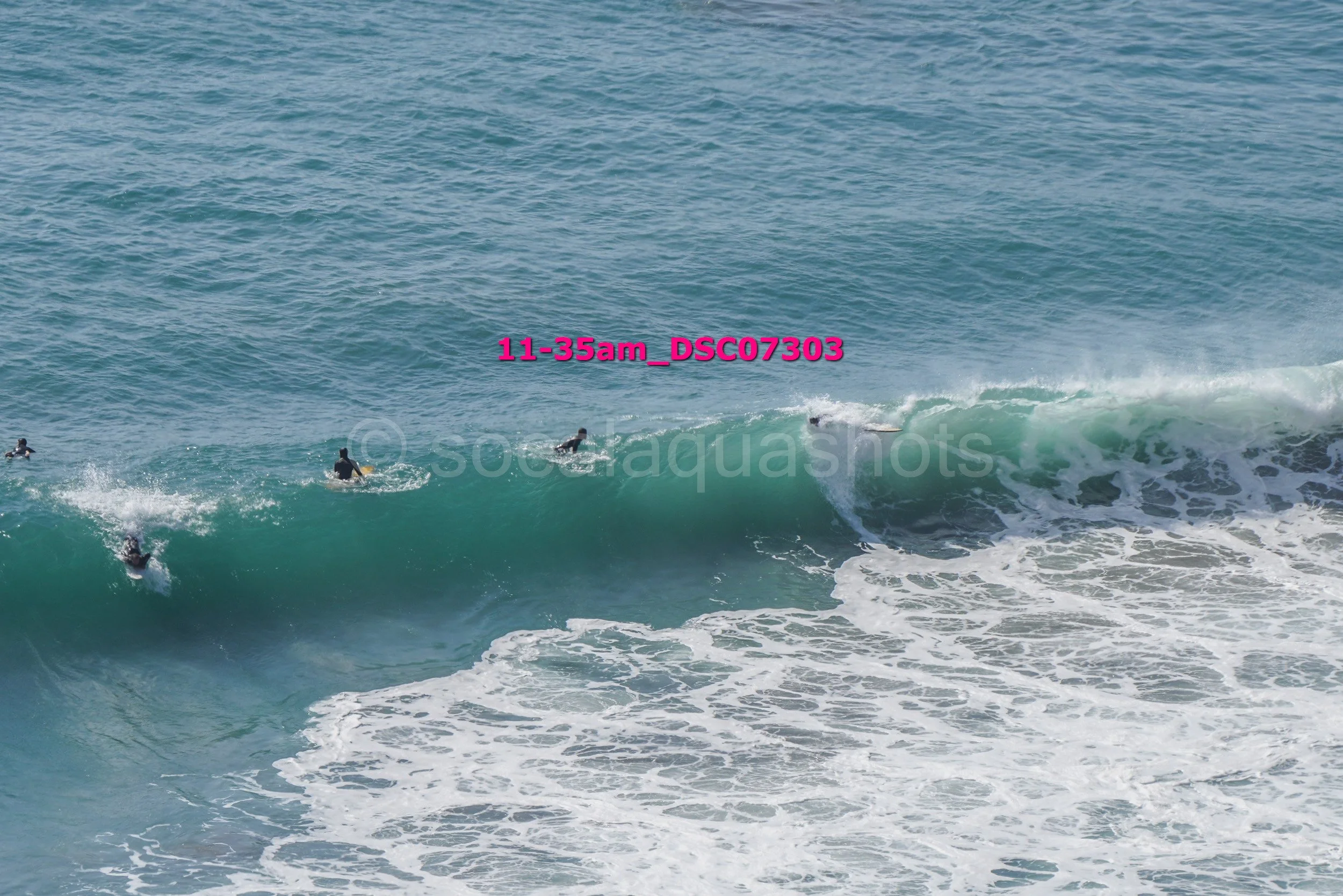Surfers riding a wave in the ocean during daytime.