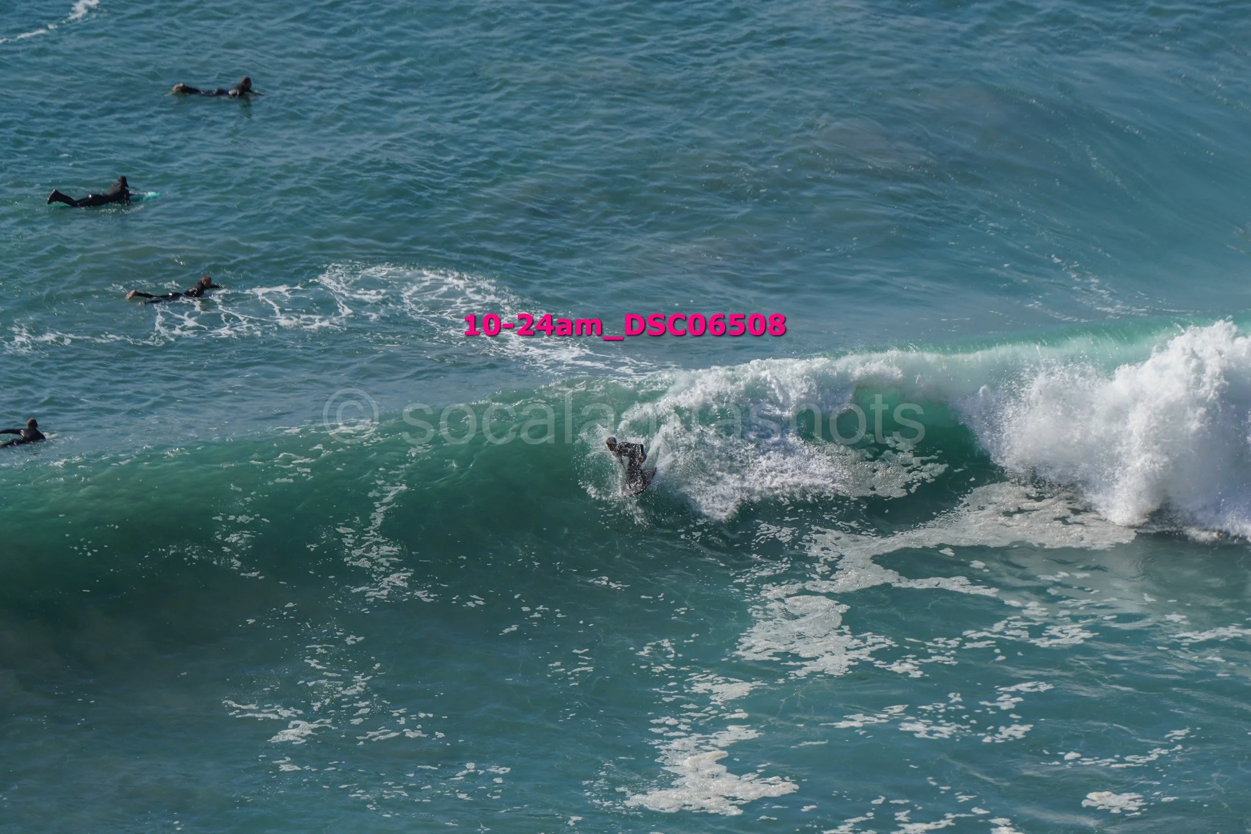 Surfer riding a wave in the ocean with other surfers nearby.