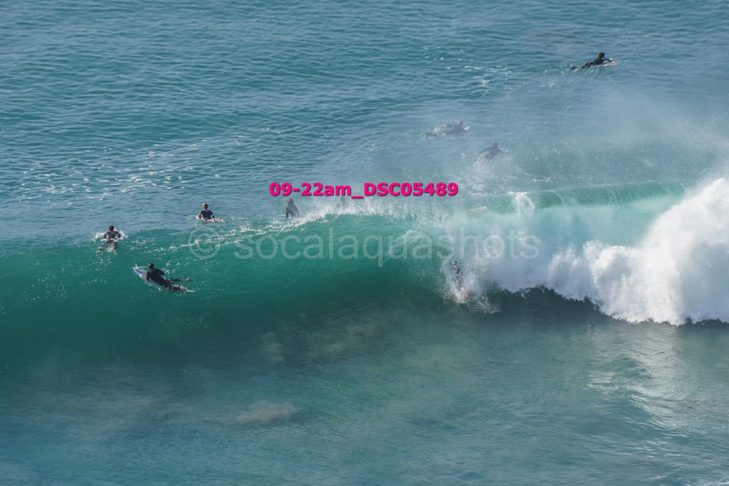 Surfers riding a large ocean wave with some surfers in the water.