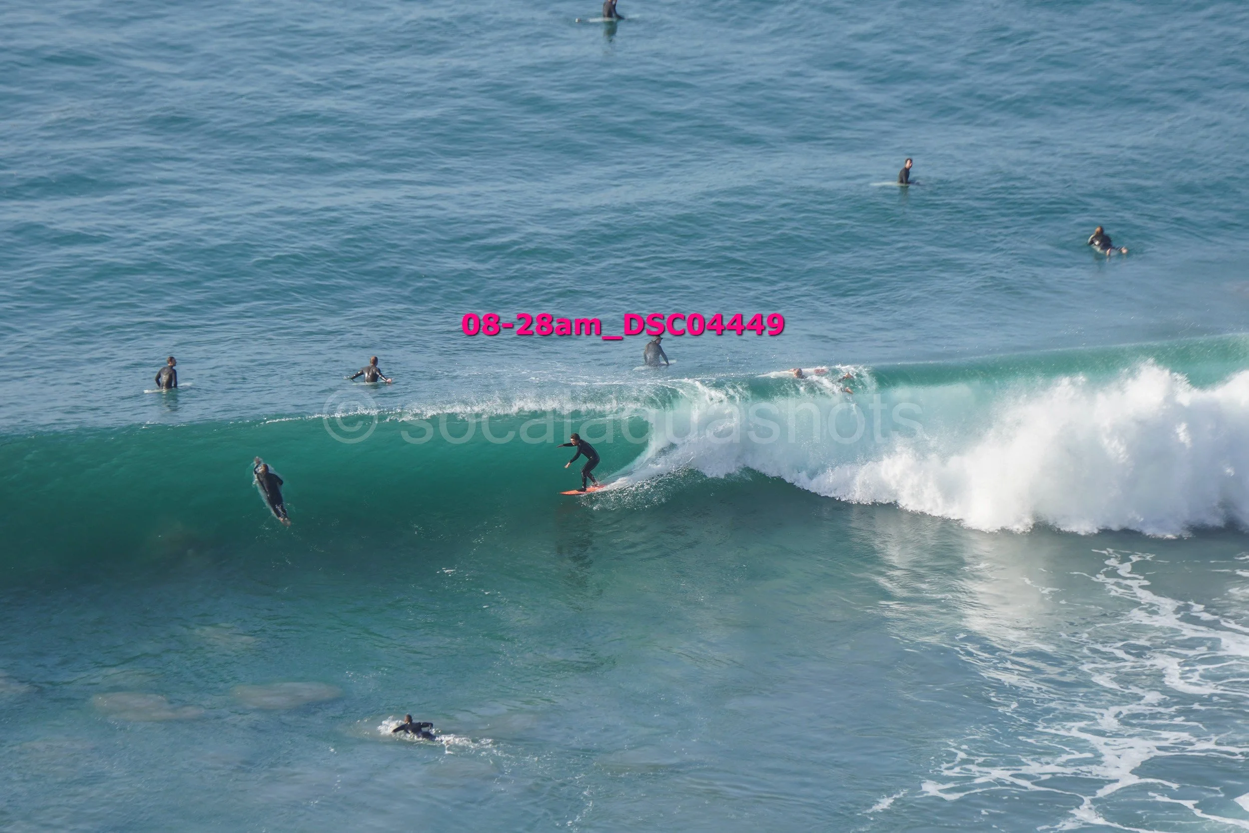 A surfer riding a large wave with other surfers in the water around him.