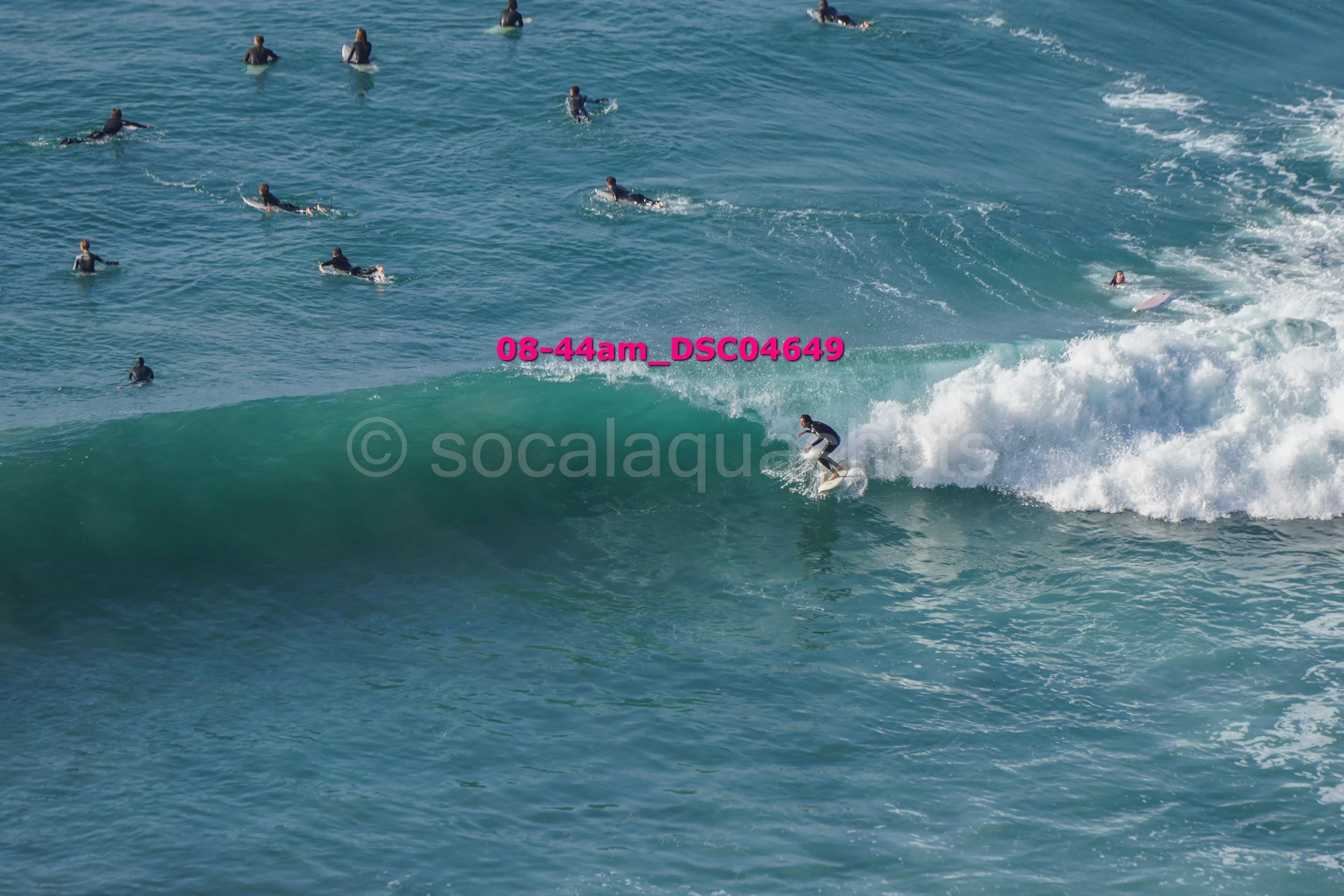 Surfer riding a wave with multiple surfers in the water.