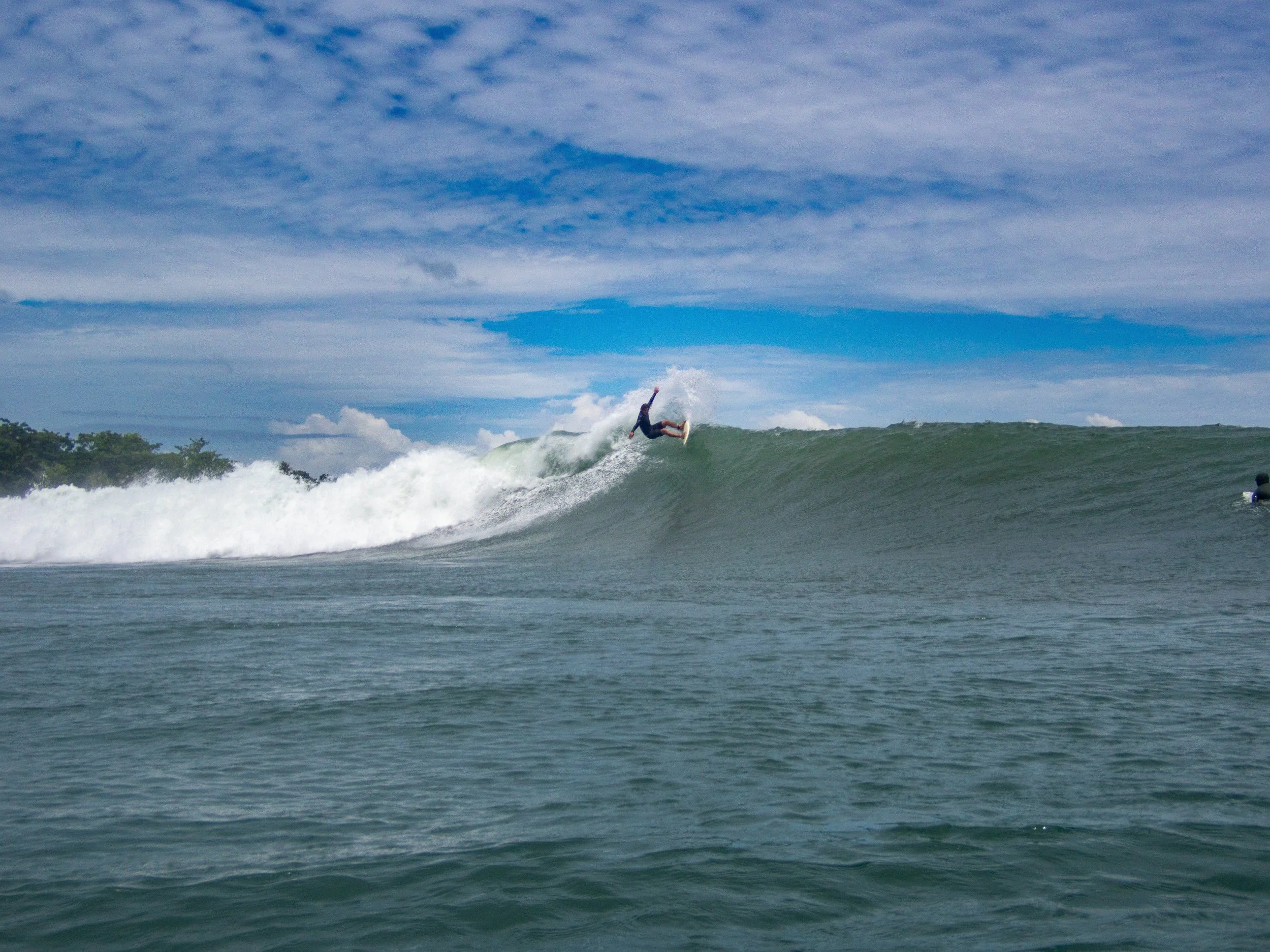 Surfer riding a large wave on a cloudy day
