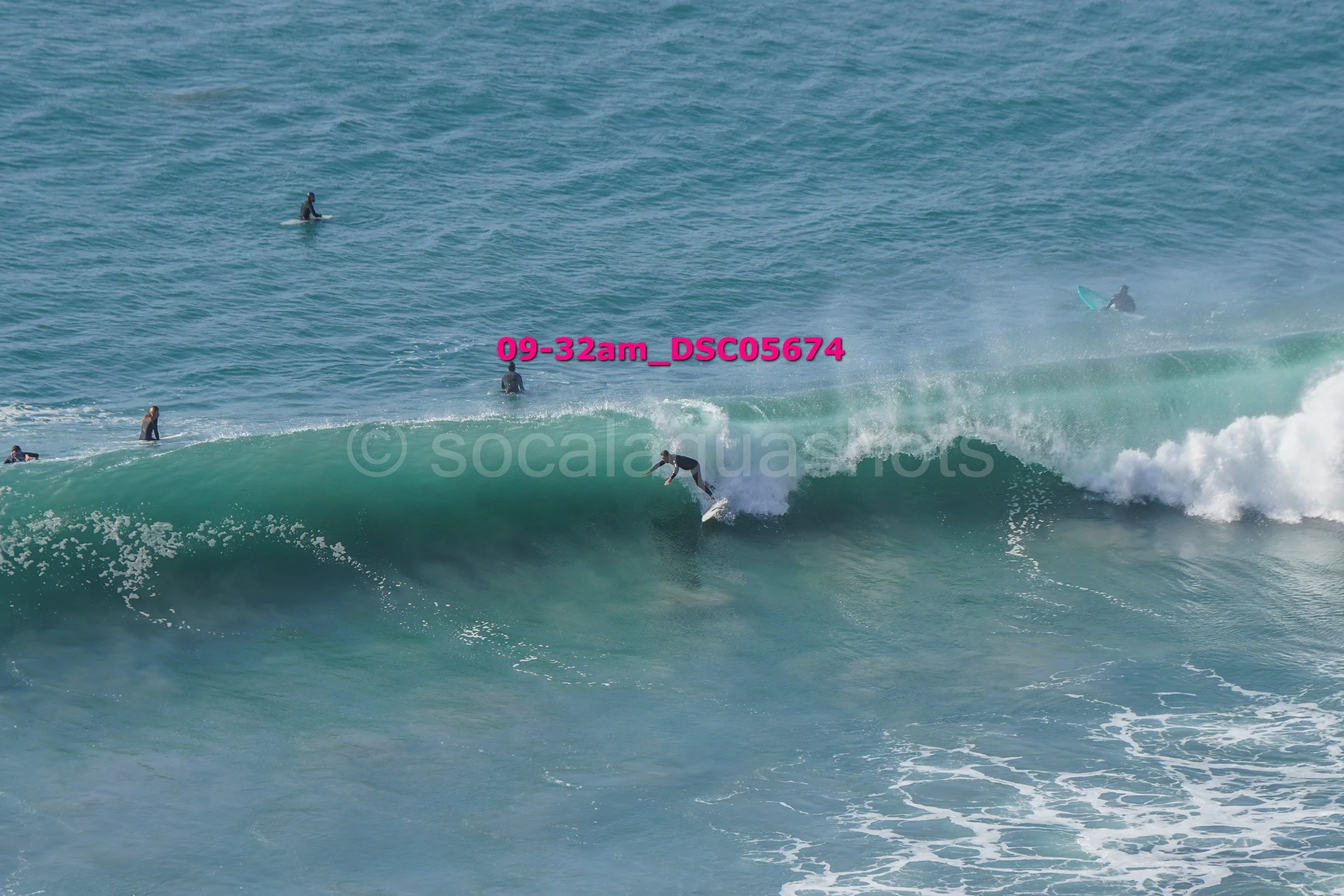 Surfer riding a wave with several people in the water watching