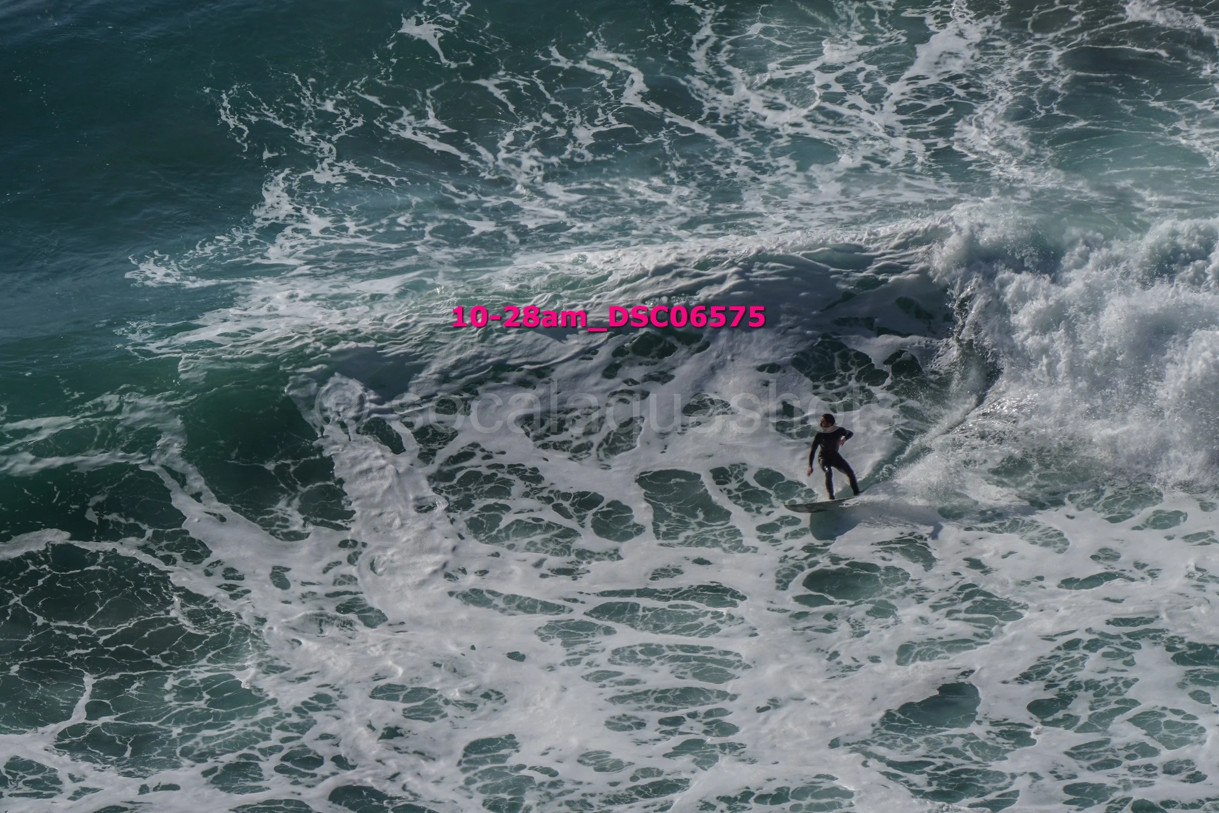 A surfer riding a wave in the ocean, with white foam and churning water around them.