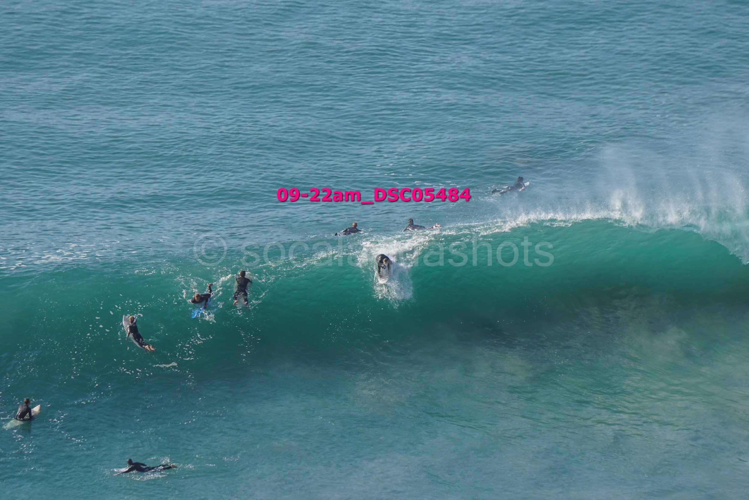 Surfers riding and paddling on ocean waves in the water. Some surfers are on their boards, others are swimming or paddling towards the wave.