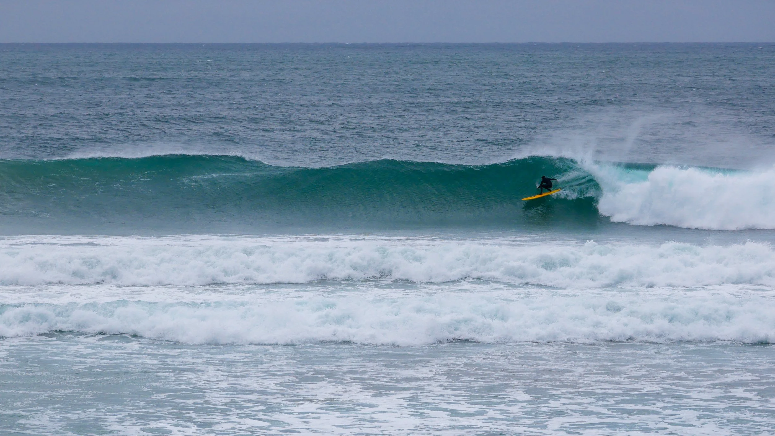 Surfer on yellow board riding a large ocean wave