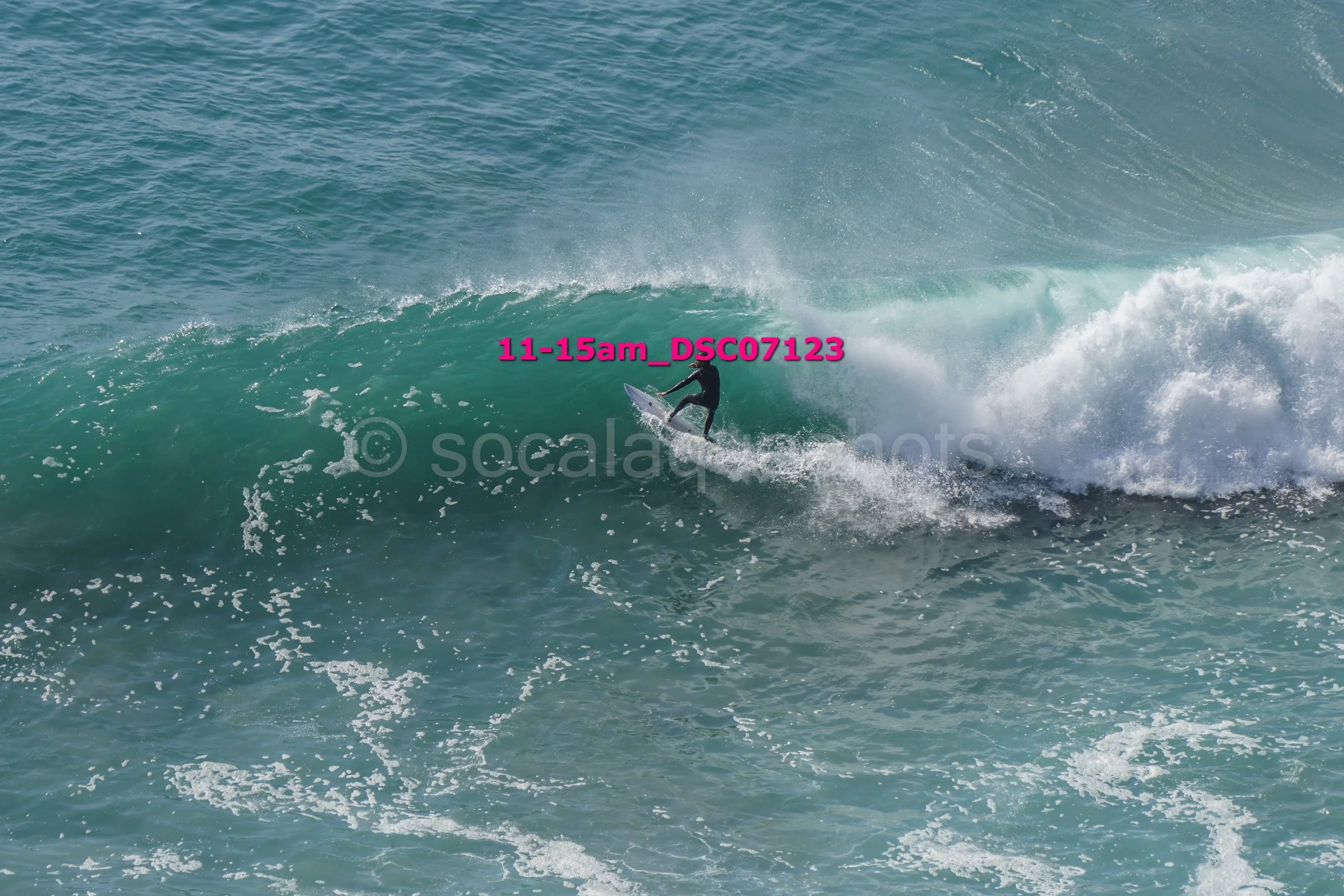 A person surfing on a large ocean wave with visible white foam and spray.