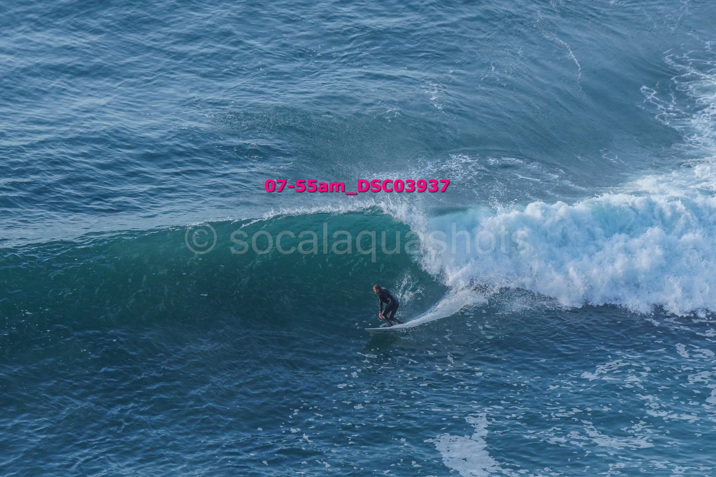 A person surfing on a large ocean wave during daylight.