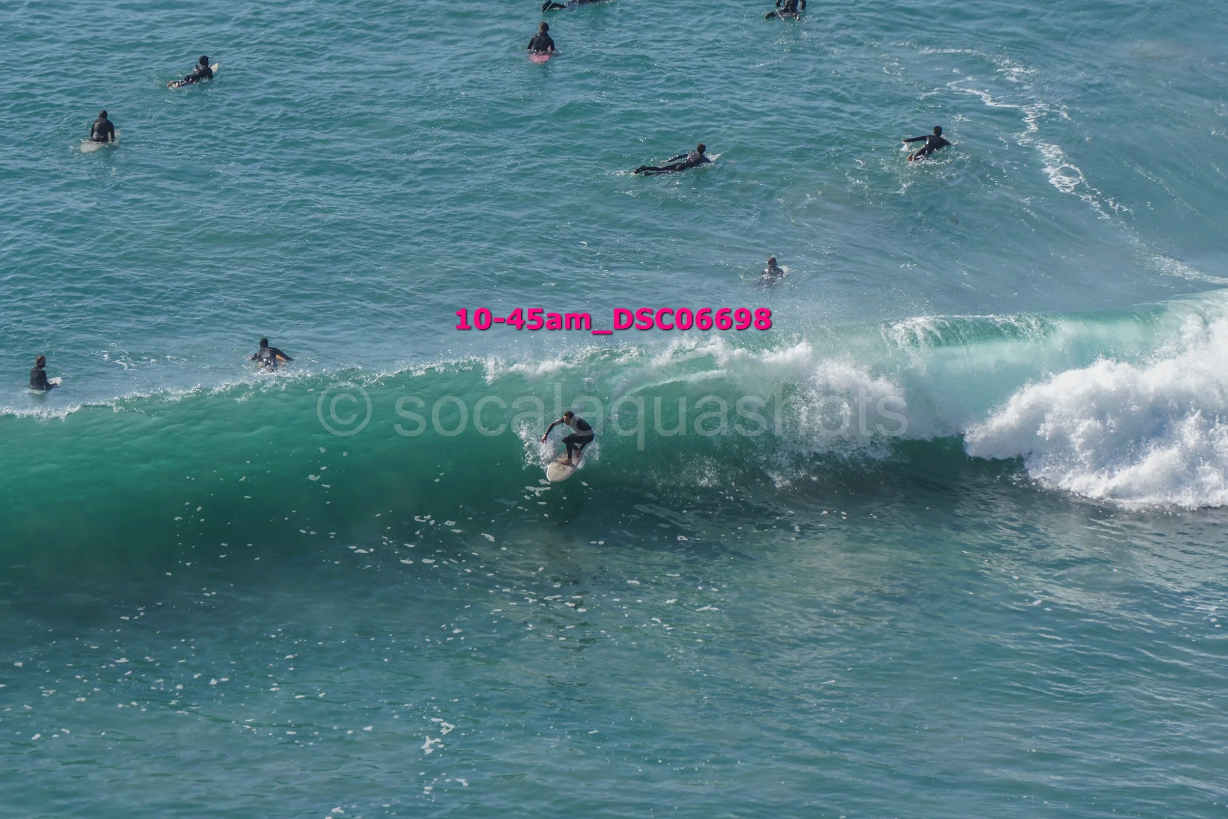 A person surfing on a wave with multiple surfers in the water in the background.