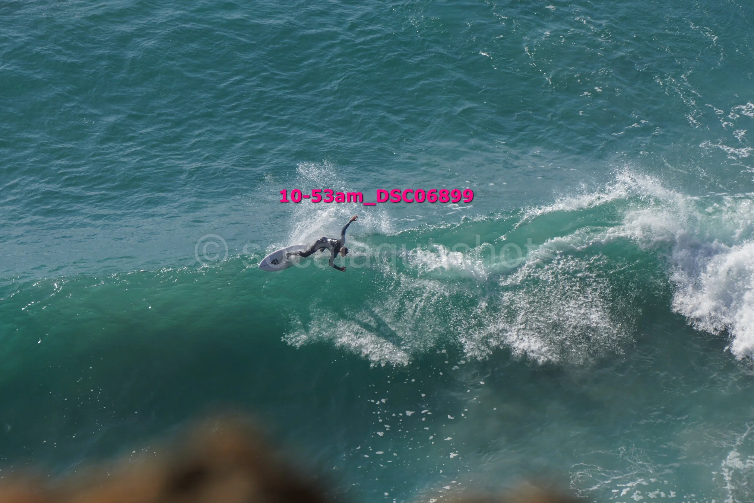 A person in a wetsuit falls off a surfboard while riding a wave in the ocean.