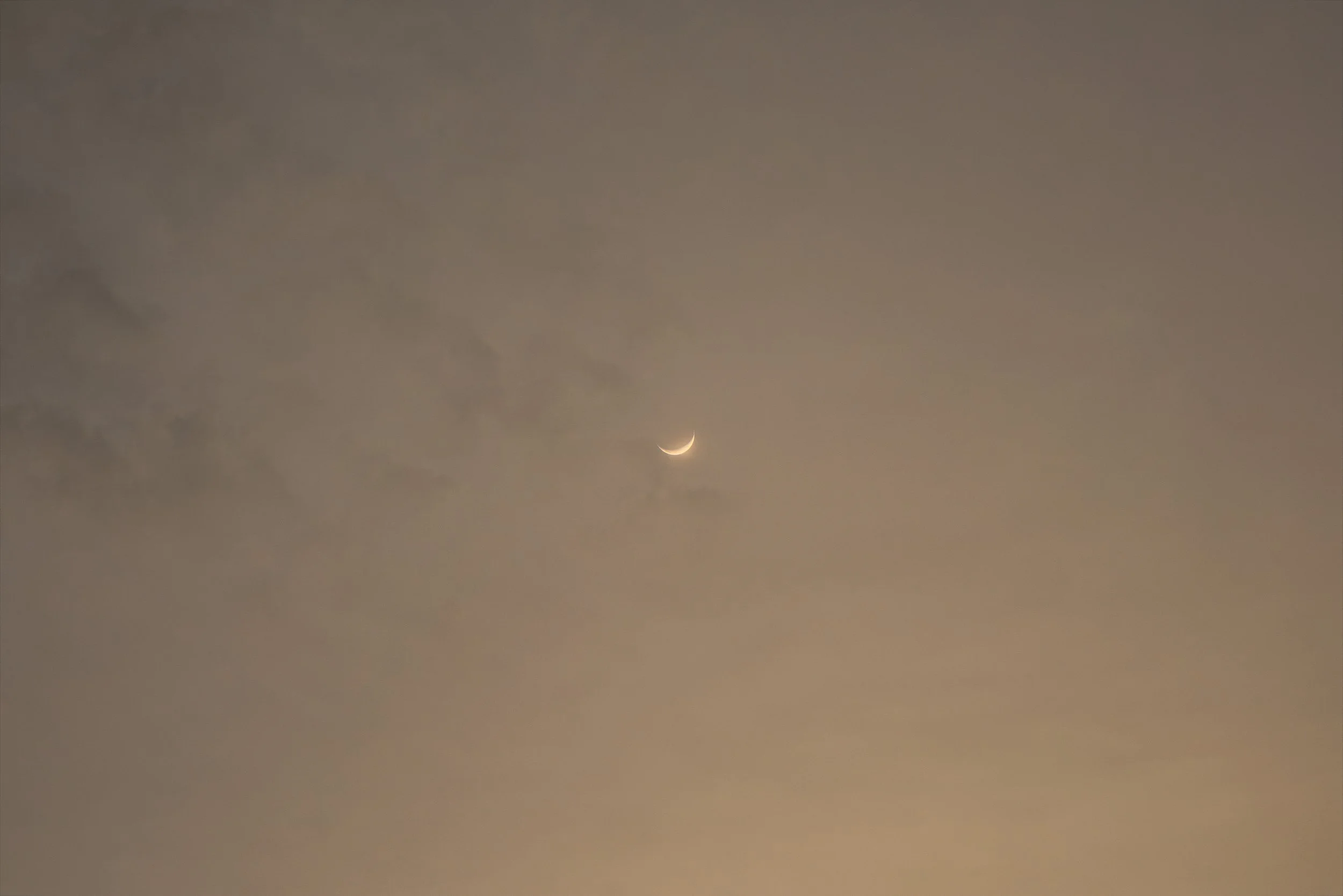 A crescent moon in a cloudy sky.