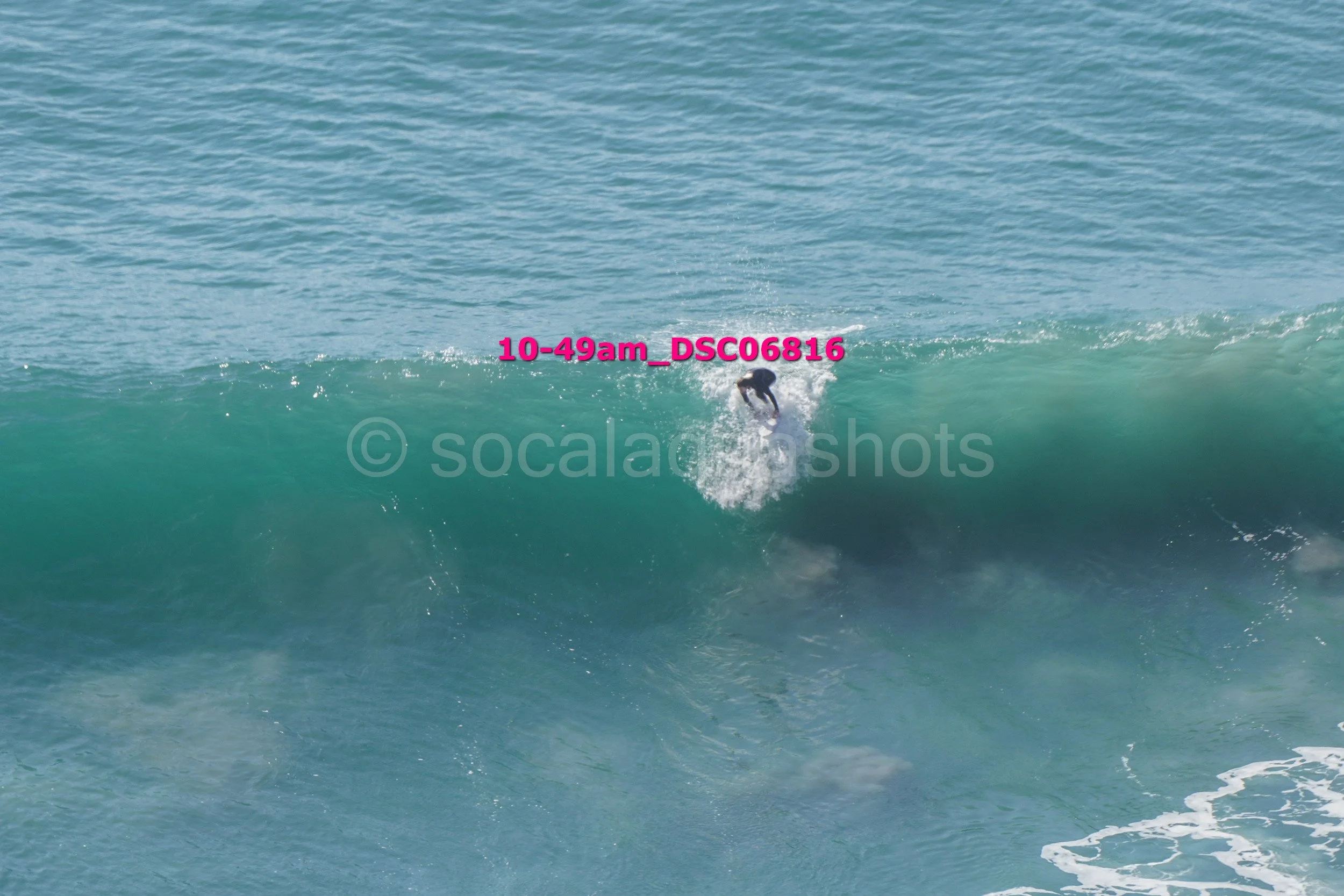 Surfer riding a wave in the ocean during daylight hours.