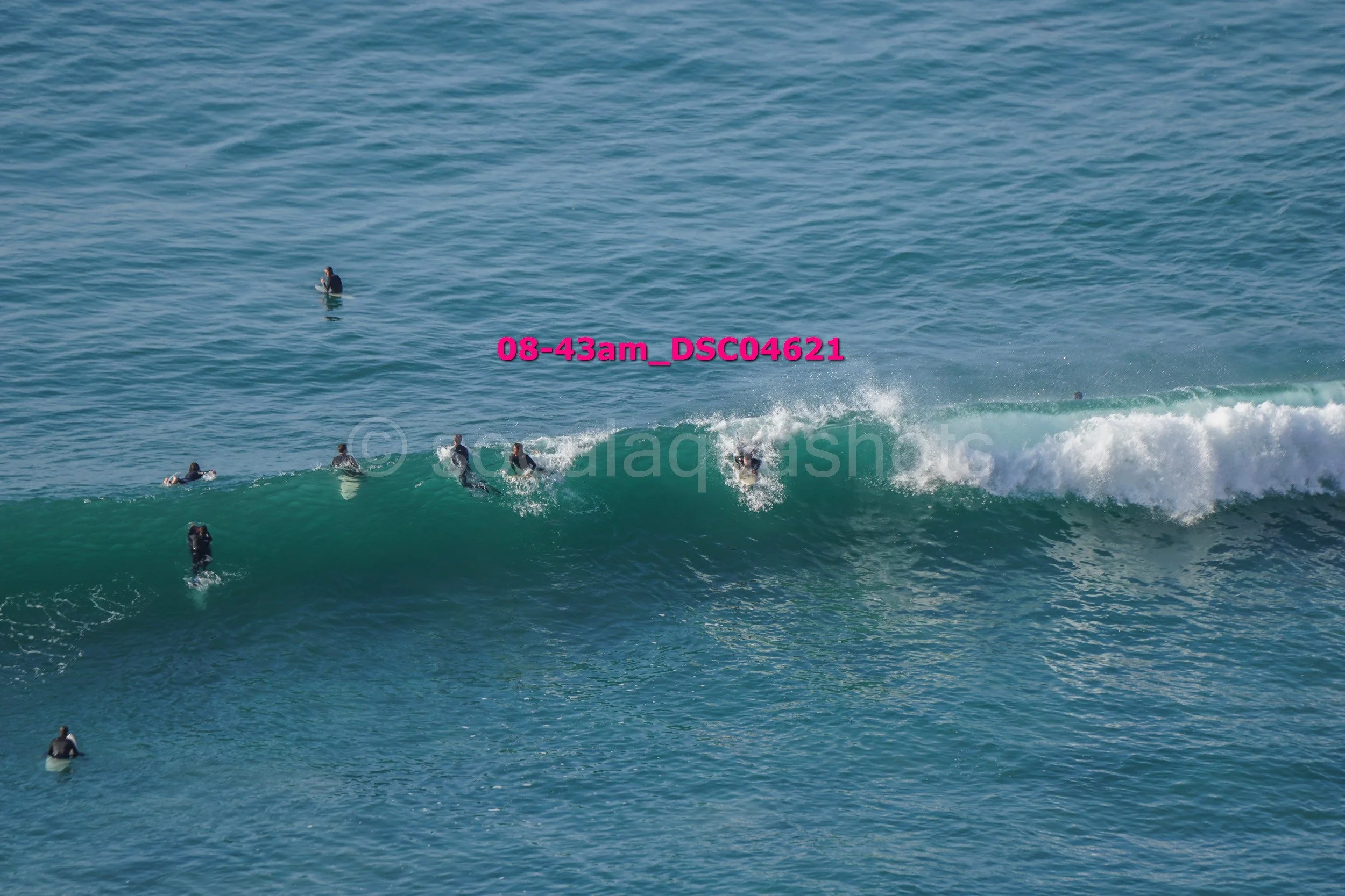 Surfers in wetsuits riding and waiting for waves in the ocean