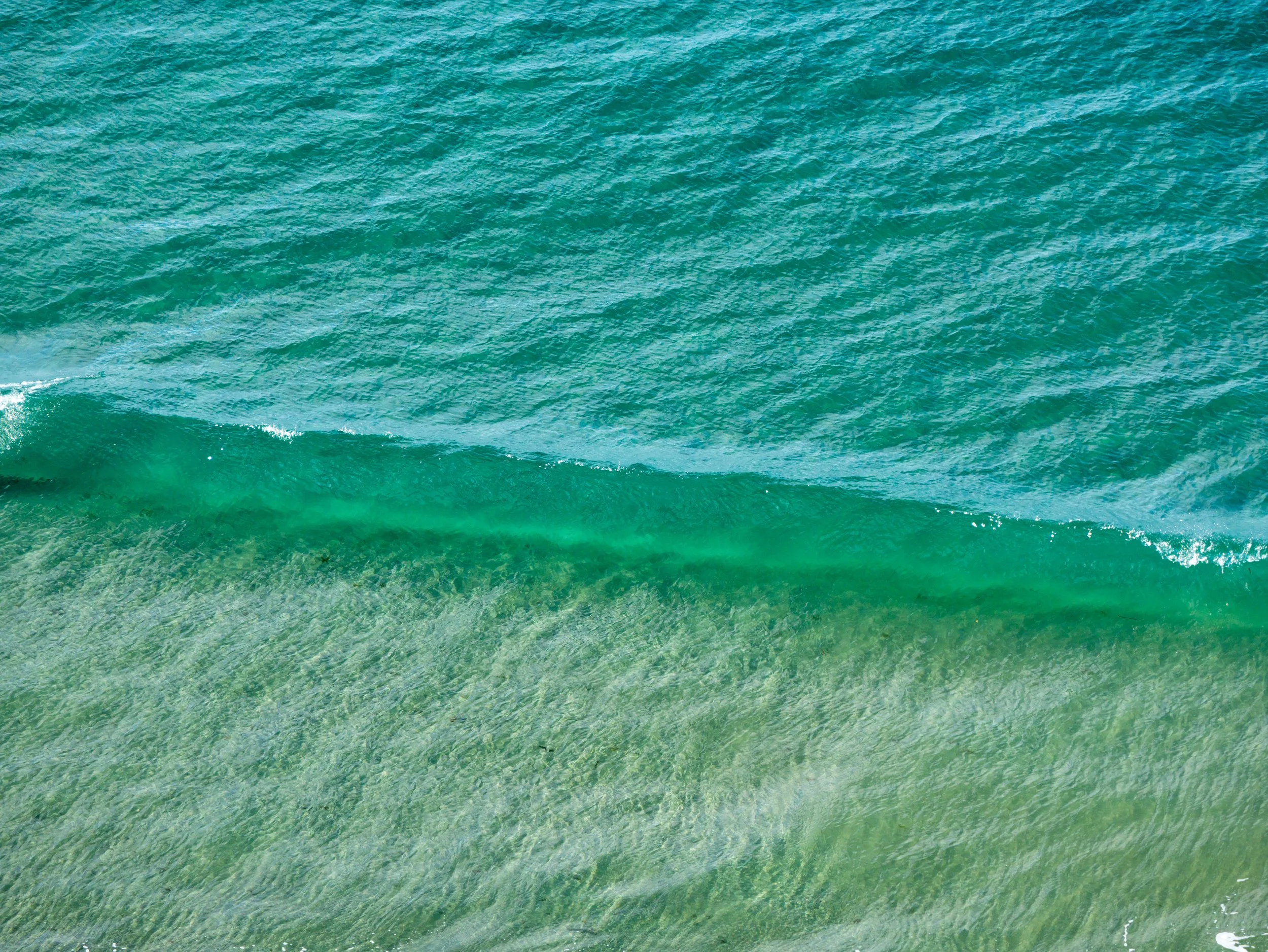 Sea wave with green and blue hues with gentle ripples.