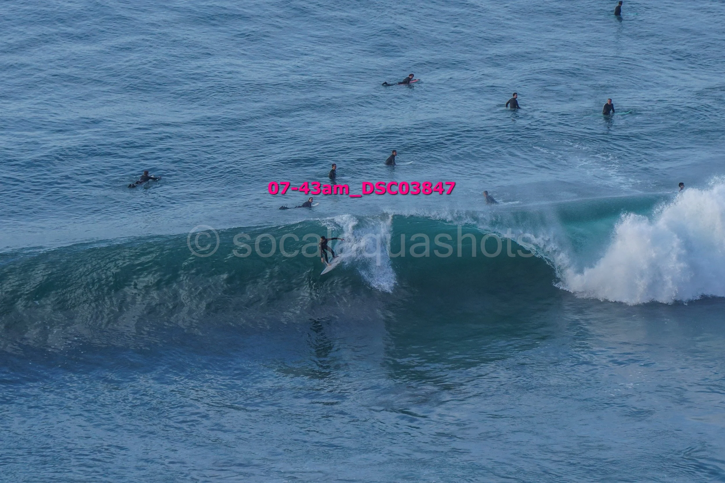 Surfer riding a wave with several people swimming or surfing in the background