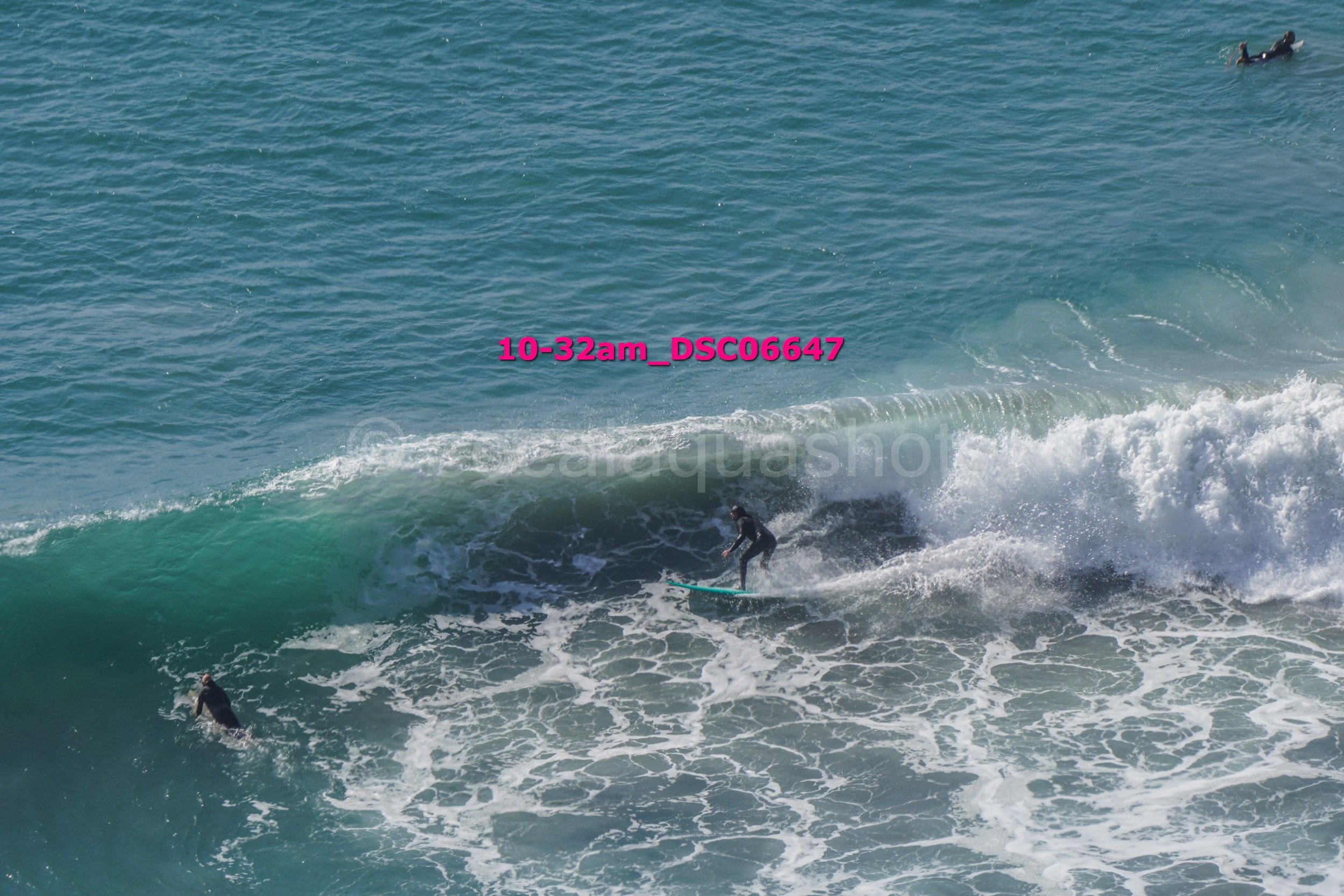 Surfer riding a wave with two other surfers in the water nearby, ocean scene