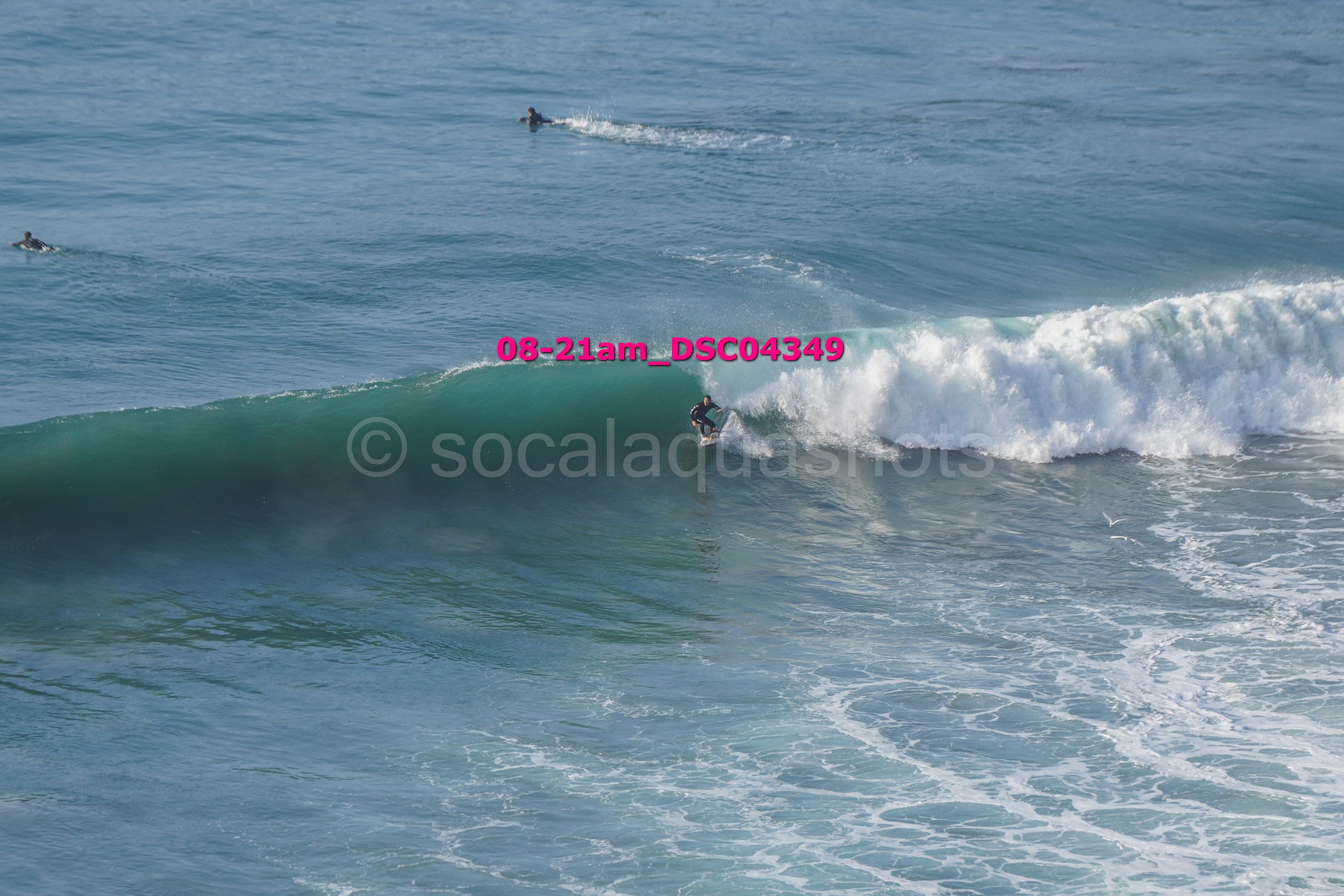 A person surfing a wave in the ocean with other surfers in the background.